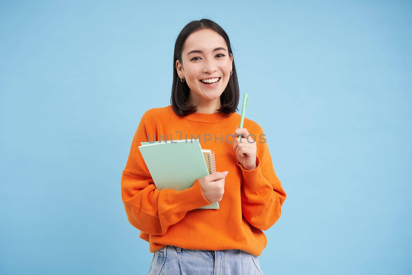 Smiling asian woman with notebooks, student with happy face, promo of college education, blue background by Benzoix