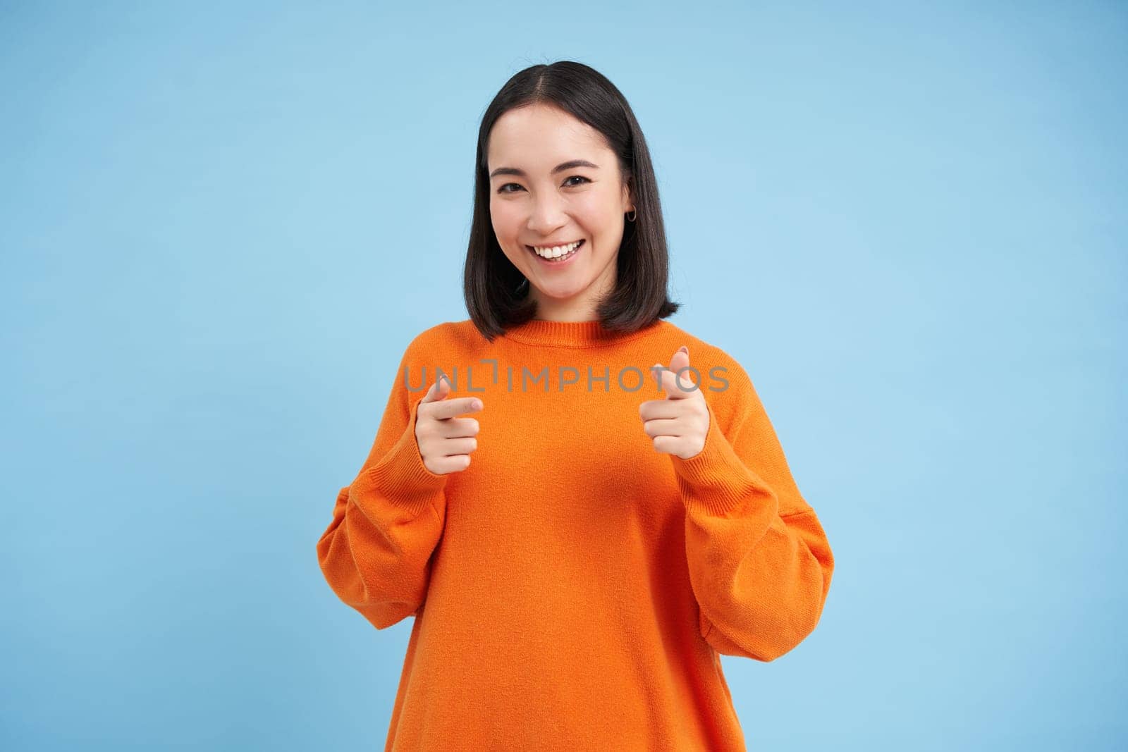 You got this, good job. Enthusiastic korean woman, points at camera with finger pistols and smiles, encourages, praises, stands over blue background by Benzoix