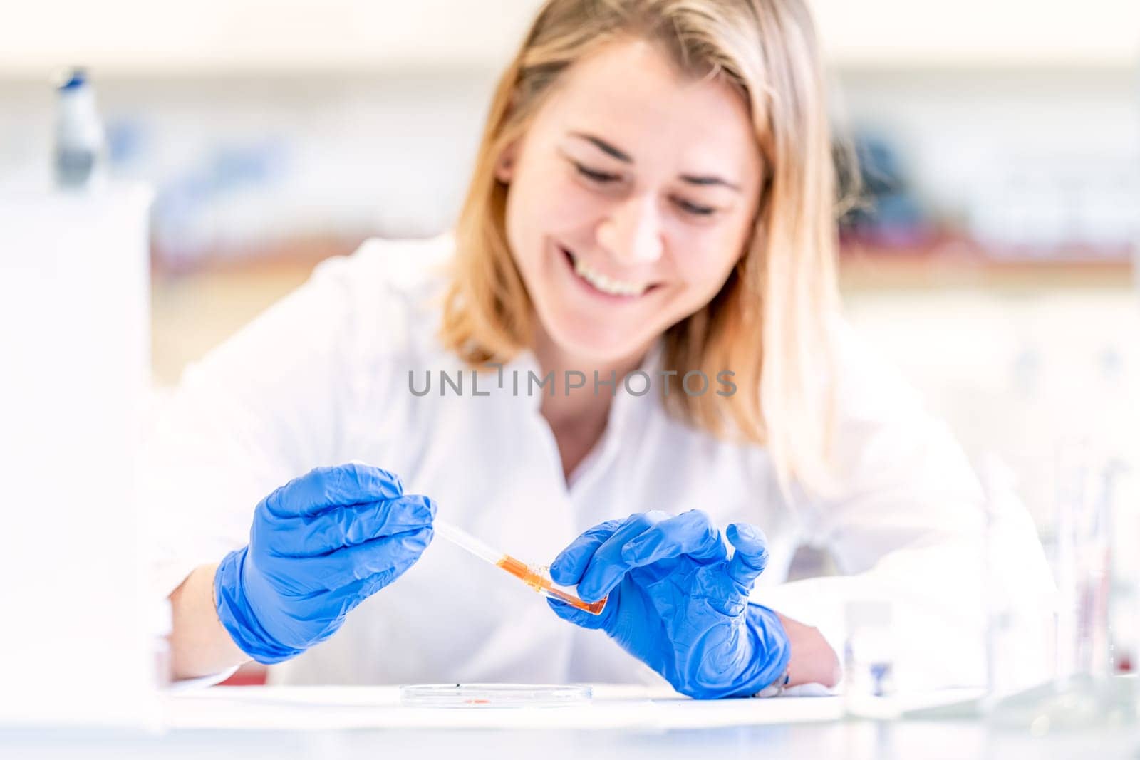 young female scientist with a smile on her face is testing a new invention in a research laboratory by Edophoto