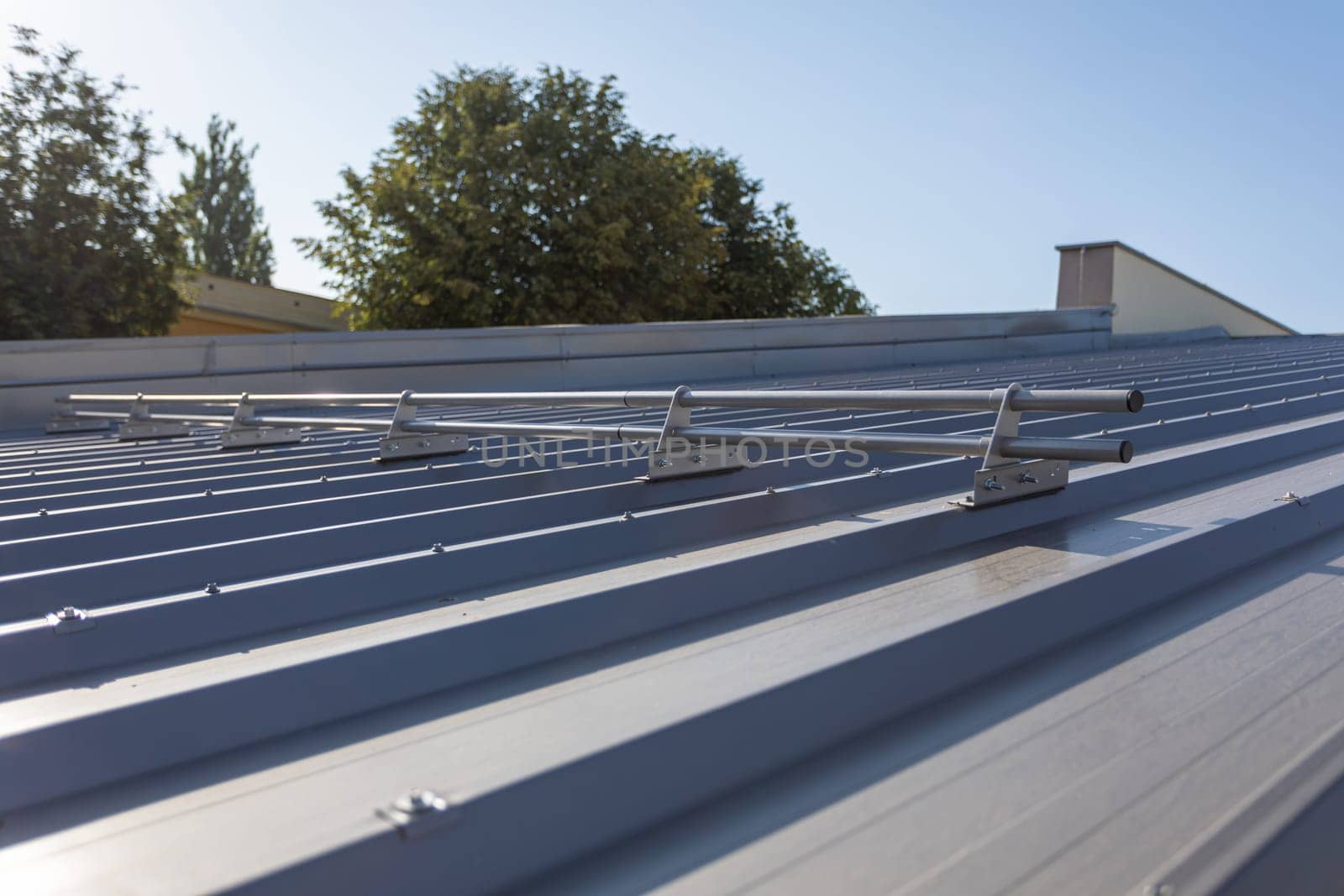 Systemic protection on the roof against sliding snow. Steep roof covered with trapezoidal sheets coated with graphite-colored paint.