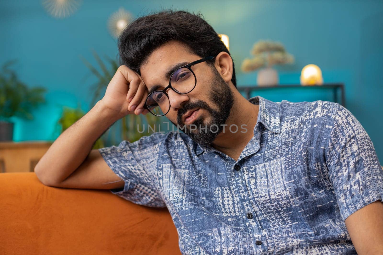 Sad lonely man sitting at home room looks pensive thinks over life concerns or unrequited love suffers from unfair situation. Hindu alone guy problem, break up, depressed feeling bad annoyed burnout