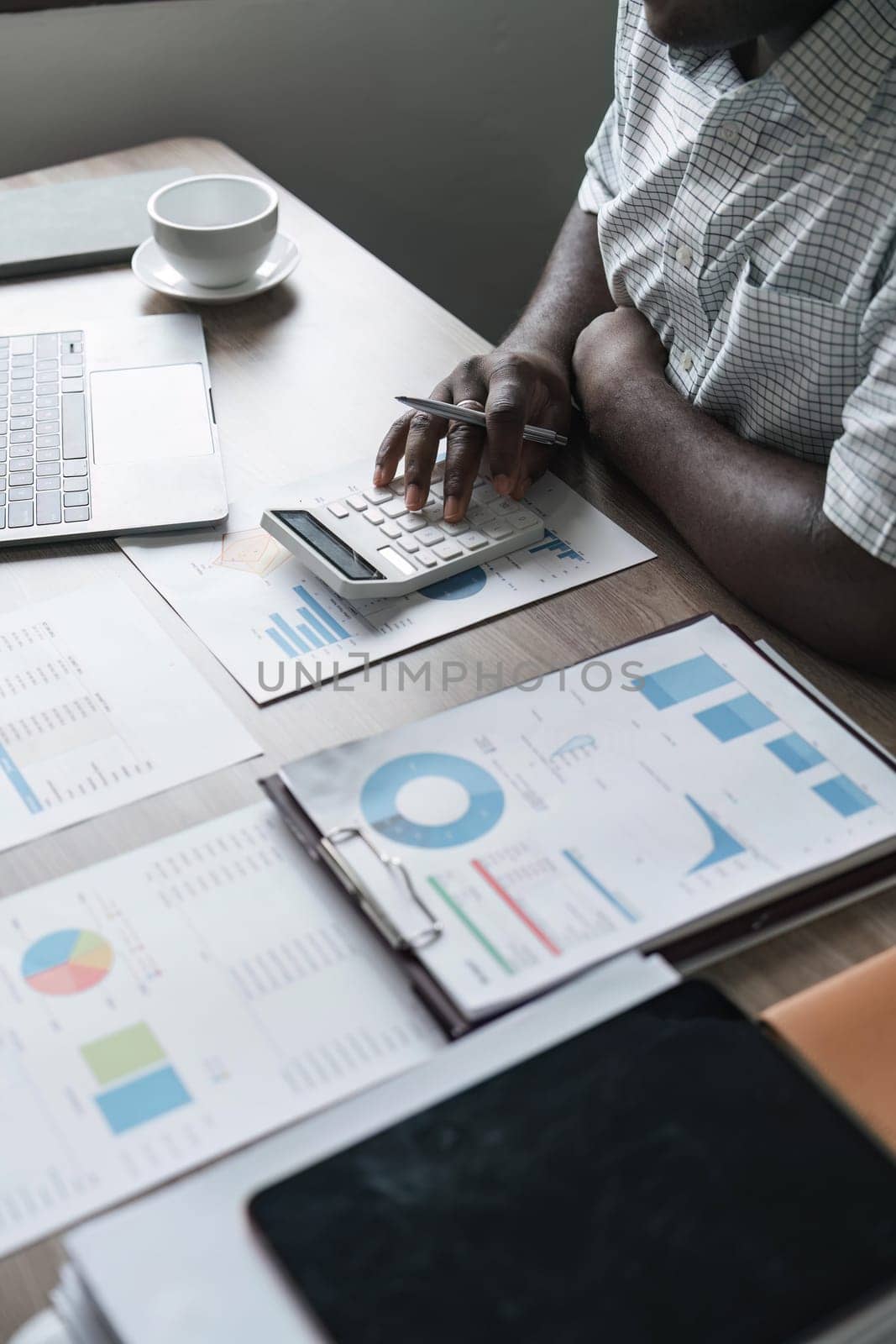 African American man calculating using machine managing household finances at home, focused biracial male make calculations on calculator account taxes or expenses.