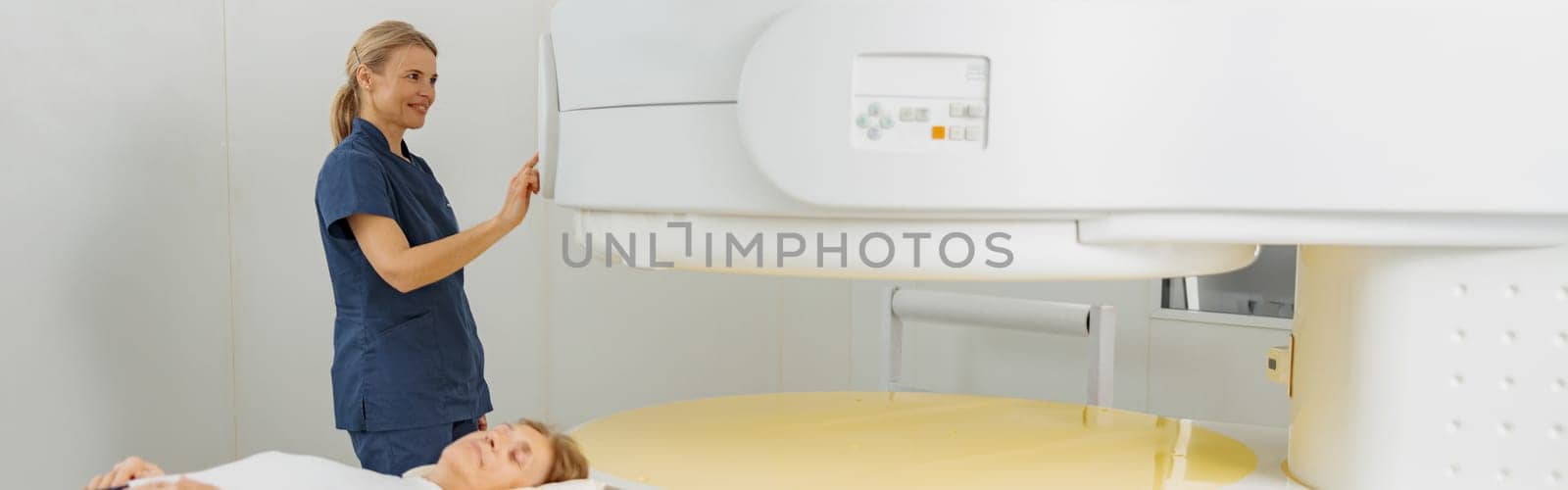 Radiologist controls MRI or CT or PET Scan with female patient undergoing procedure by Yaroslav_astakhov