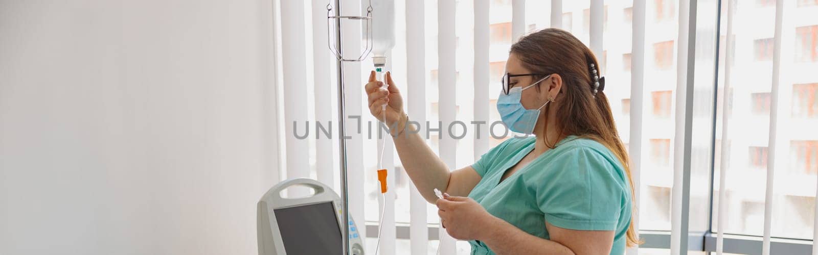 Nurse in mask controls drip of her patient during Covid-19 epidemic by Yaroslav_astakhov