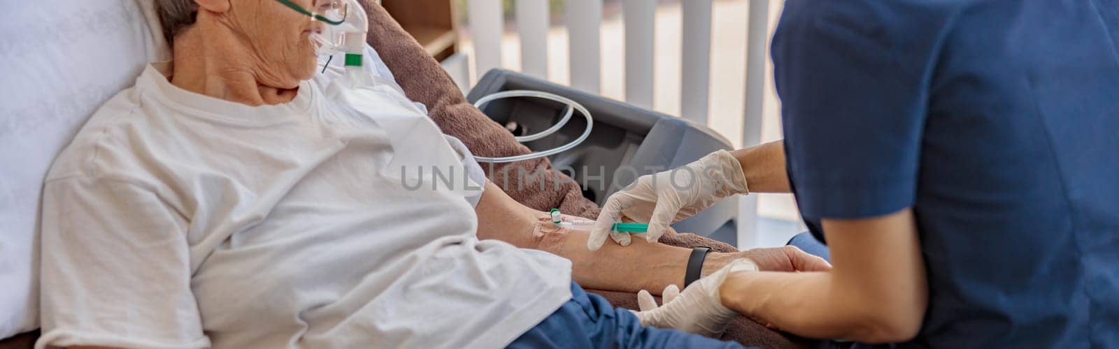 Nurse putting drip on the arm of her patient in mask during pandemic of Covid 19. High quality photo