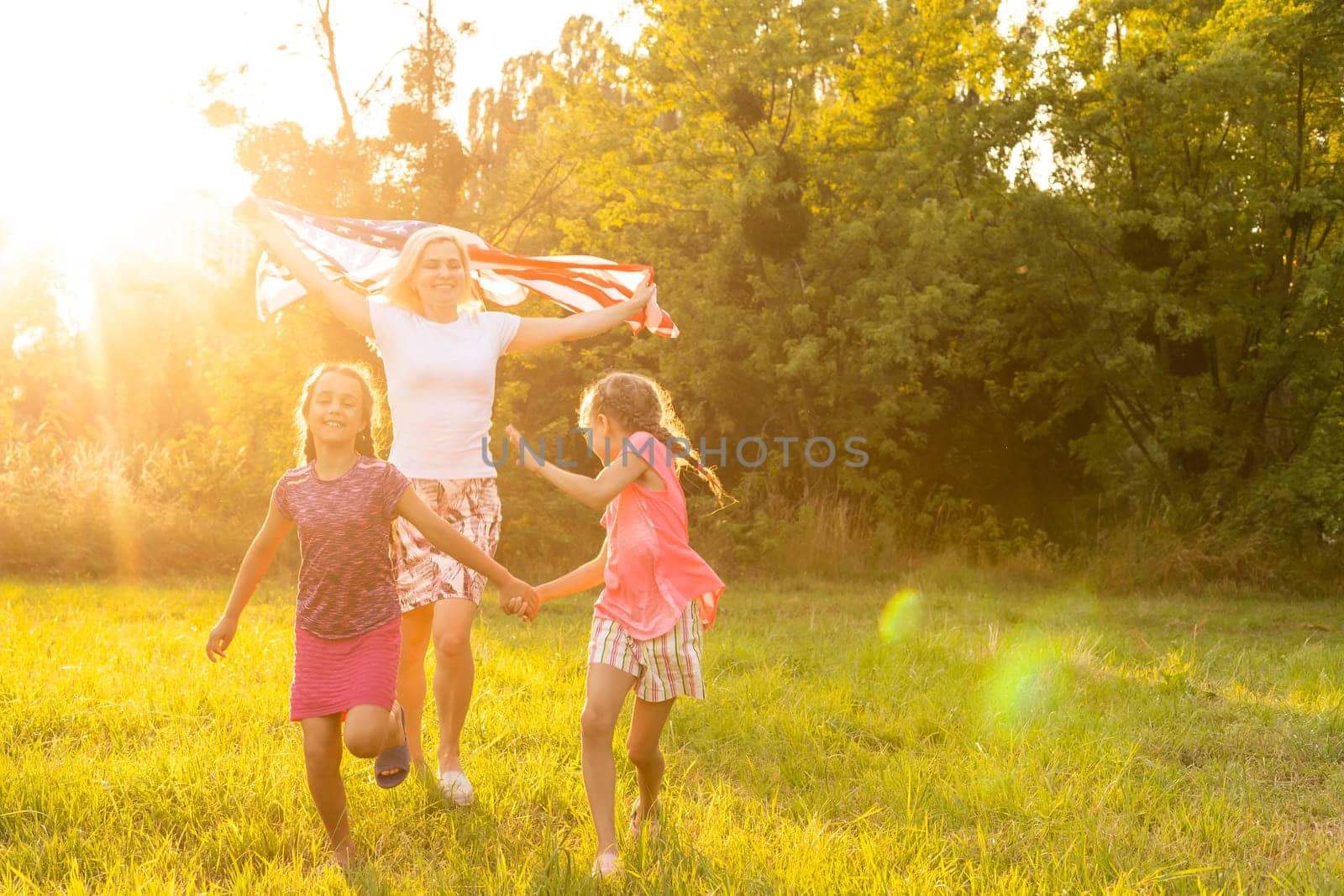 happy family with the flag of america USA at sunset outdoors by Andelov13