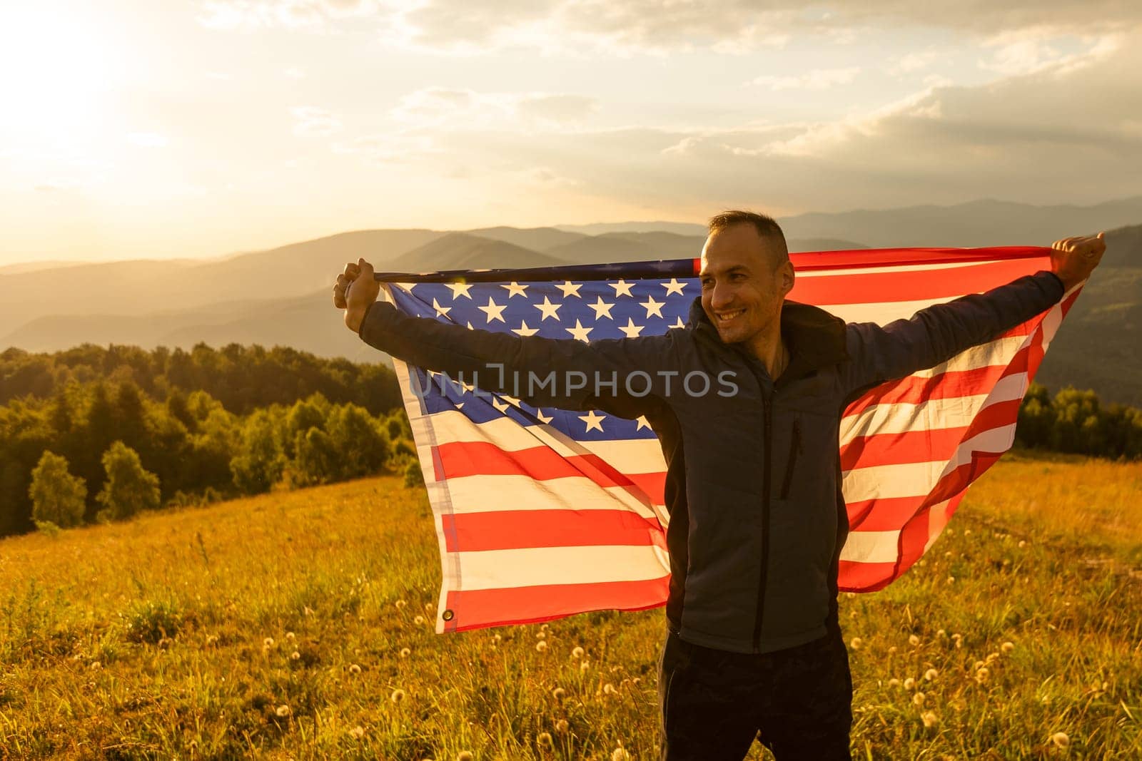 successful silhouette man winner waving American flag on top of the mountain.