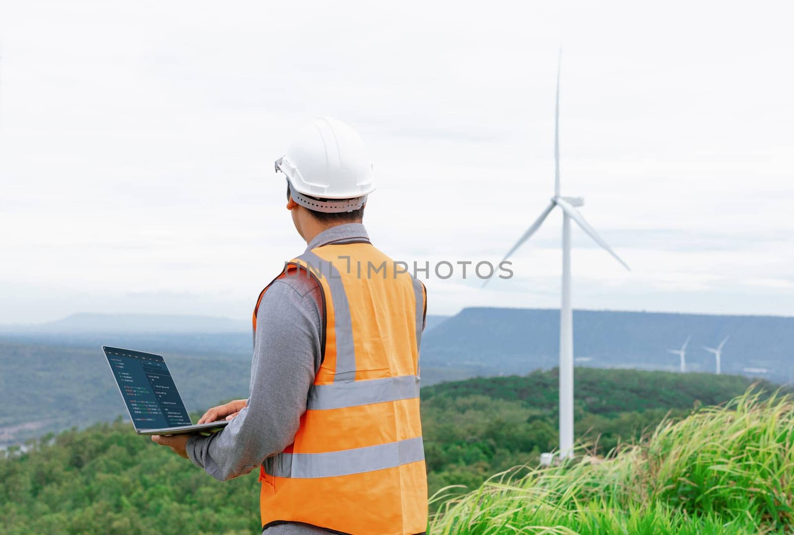 Progressive concept of engineer working in the wind farm atop of the mountain. by biancoblue