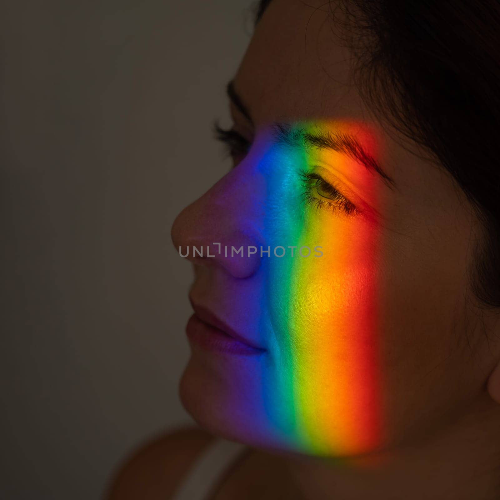 Close-up portrait of caucasian woman with ray of rainbow light on her face
