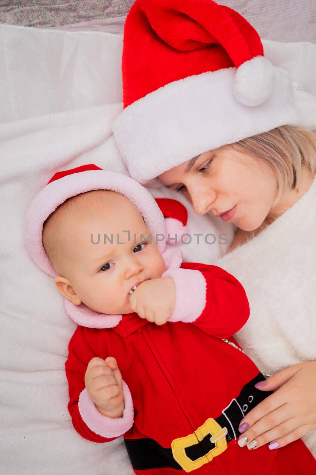 Caucasian woman hugging baby son in santa claus costume