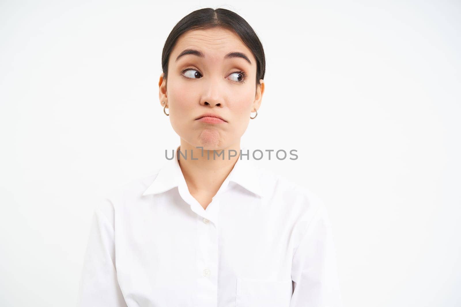 Portrait of businesswoman, asian lady looks surprised at right side banner, stands isolated on white background.