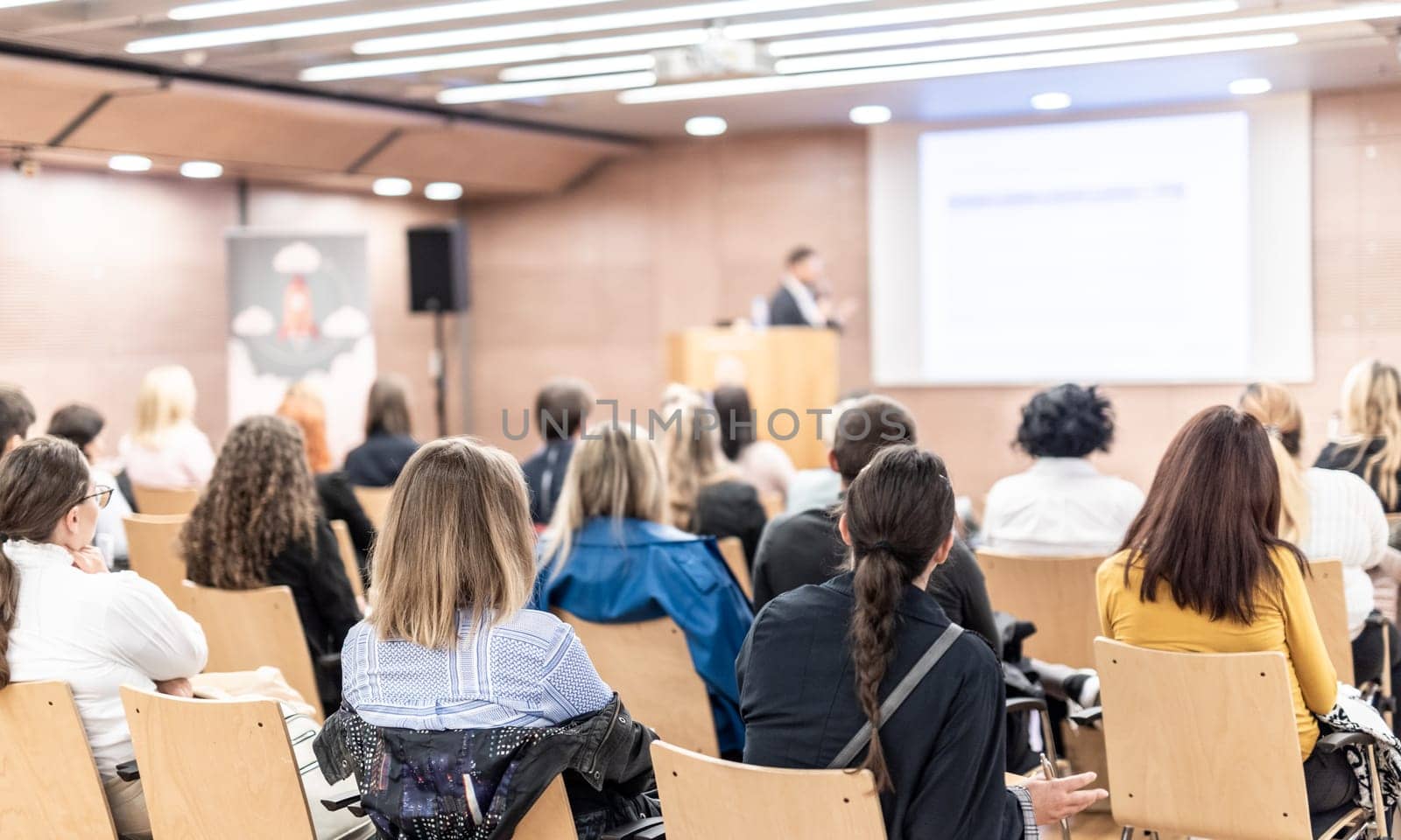 Speaker giving a talk in conference hall at business event. Rear view of unrecognizable people in audience at the conference hall. Business and entrepreneurship concept