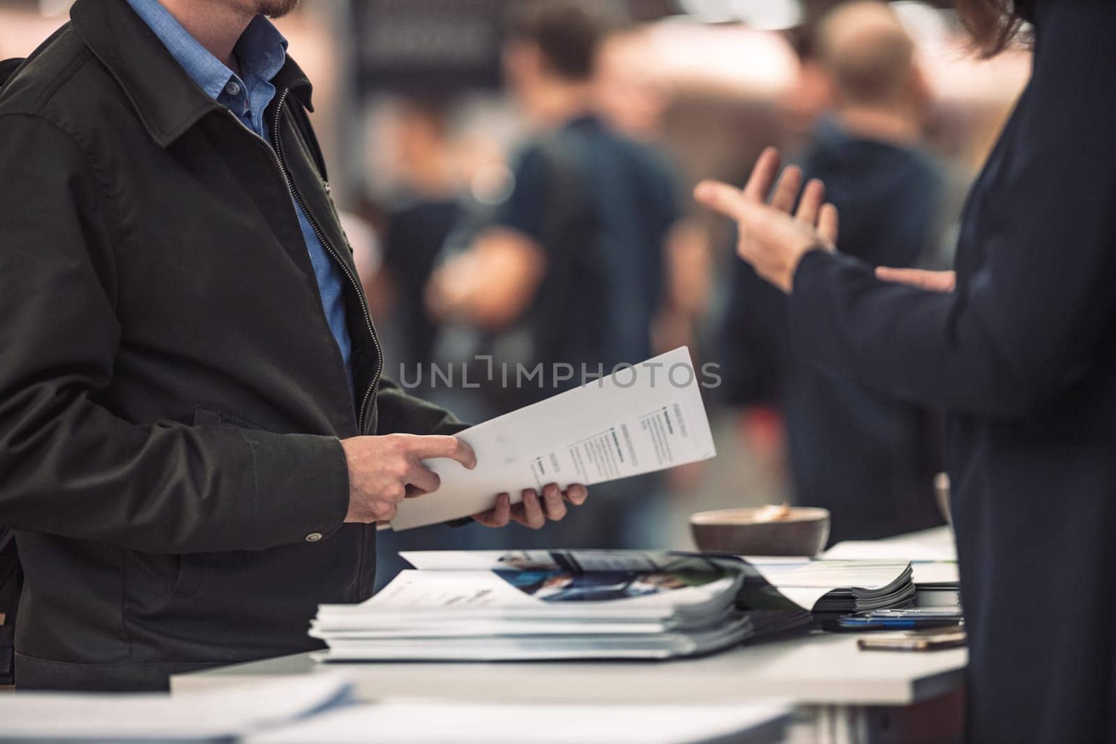 Business people exchanging business promotional materials and brochure on business meeting on trade-show. Business discussion talking deal concept