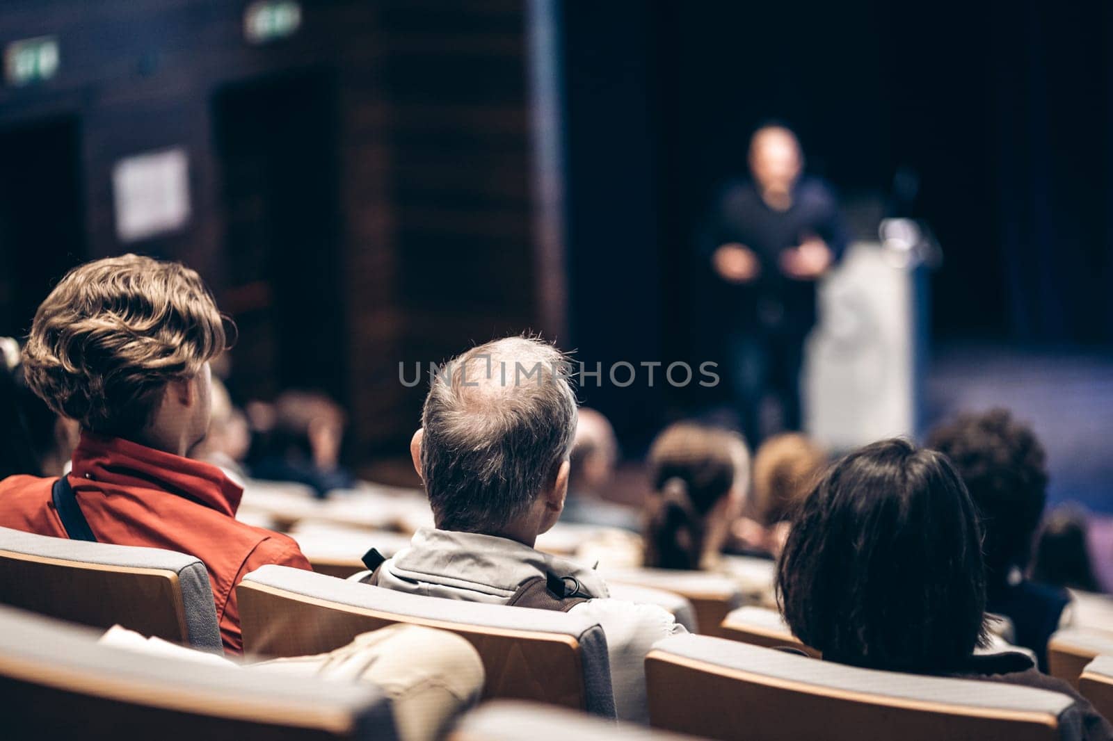 Speaker giving a talk in conference hall at business event. Rear view of unrecognizable people in audience at the conference hall. Business and entrepreneurship concept