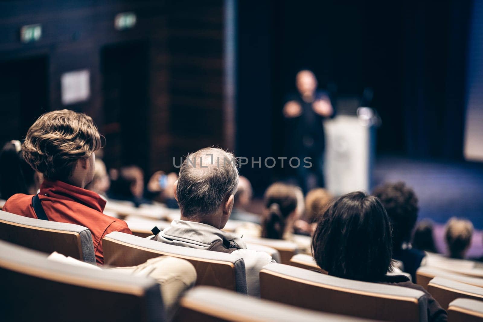 Speaker giving a talk in conference hall at business event. Rear view of unrecognizable people in audience at the conference hall. Business and entrepreneurship concept