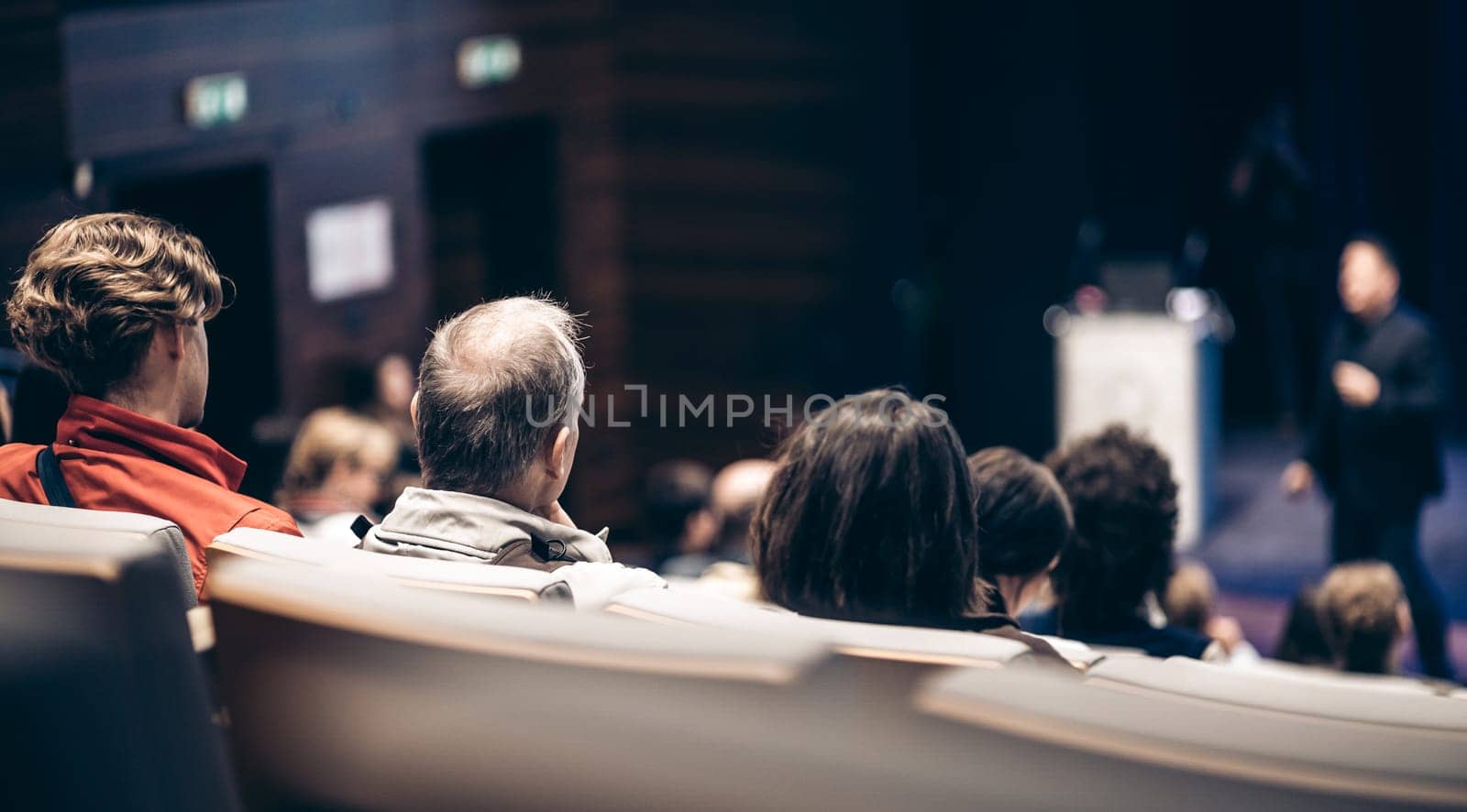 Speaker giving a talk in conference hall at business event. Rear view of unrecognizable people in audience at the conference hall. Business and entrepreneurship concept