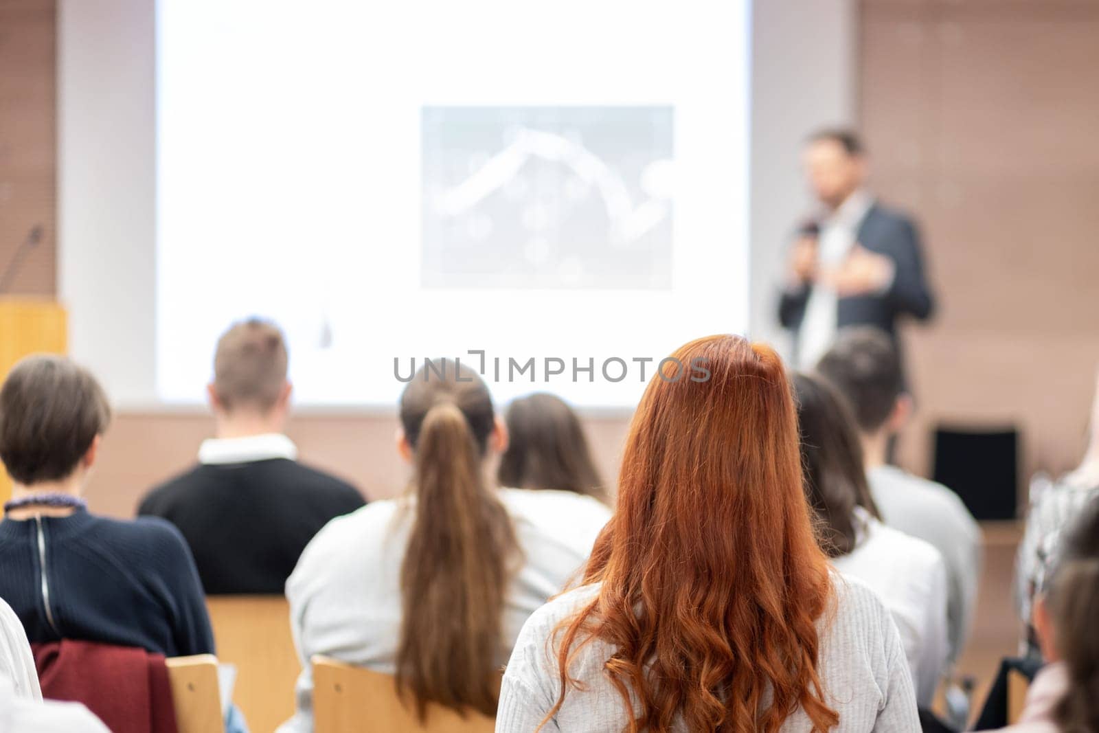 Speaker giving a talk in conference hall at business event. Rear view of unrecognizable people in audience at the conference hall. Business and entrepreneurship concept