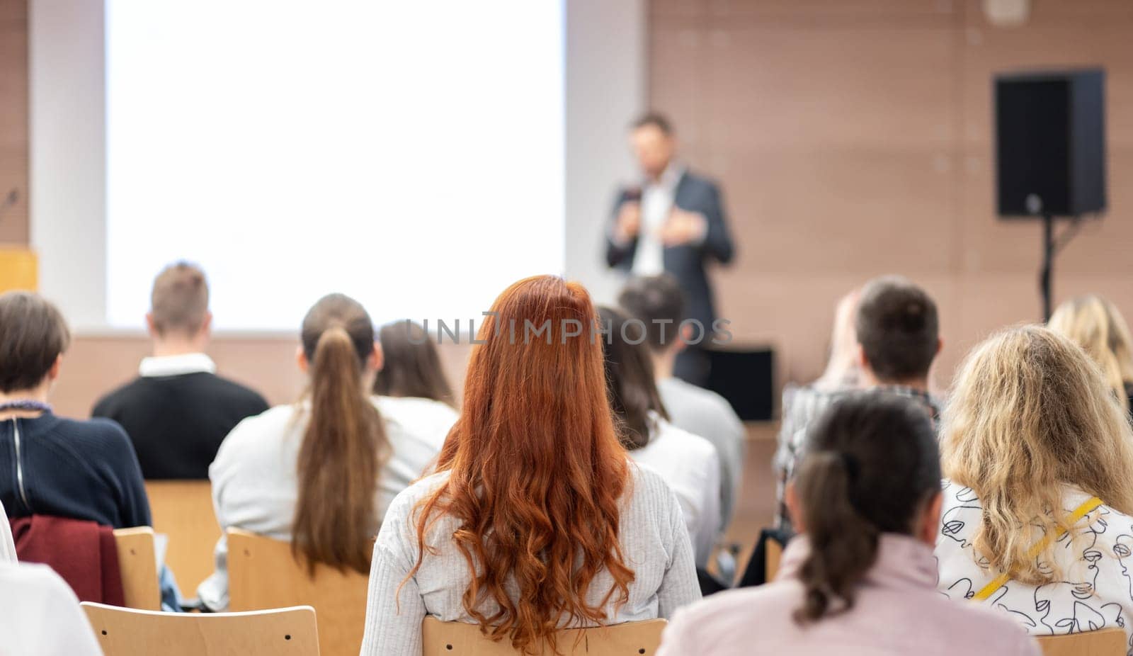 Speaker giving a talk in conference hall at business event. Rear view of unrecognizable people in audience at the conference hall. Business and entrepreneurship concept