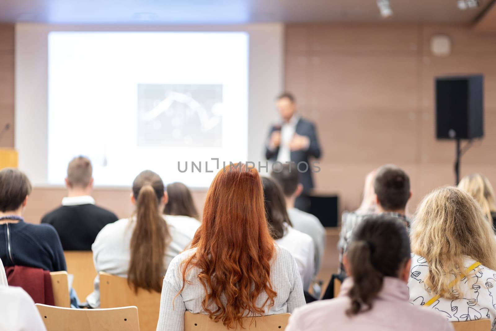 Speaker giving a talk in conference hall at business event. Rear view of unrecognizable people in audience at the conference hall. Business and entrepreneurship concept