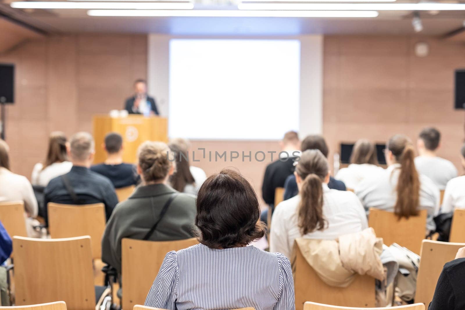 Speaker giving a talk in conference hall at business event. Rear view of unrecognizable people in audience at the conference hall. Business and entrepreneurship concept