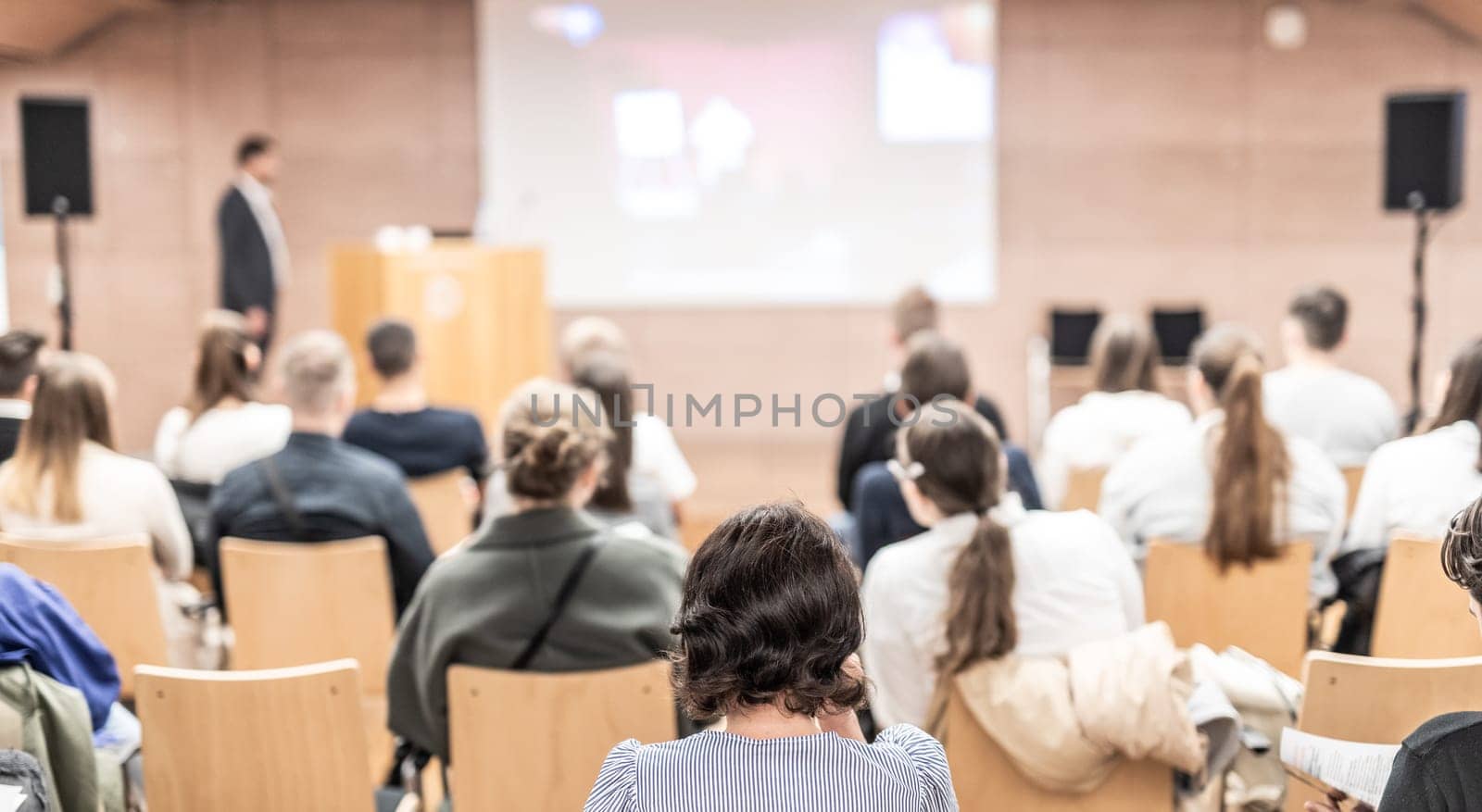 Speaker giving a talk in conference hall at business event. Rear view of unrecognizable people in audience at the conference hall. Business and entrepreneurship concept