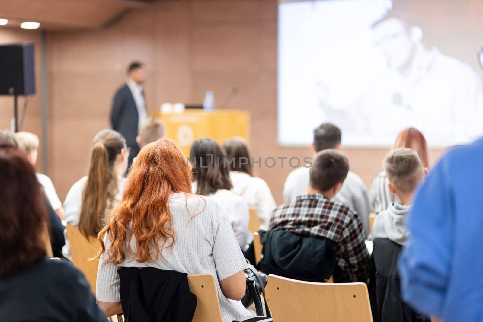 Speaker giving a talk in conference hall at business event. Rear view of unrecognizable people in audience at the conference hall. Business and entrepreneurship concept