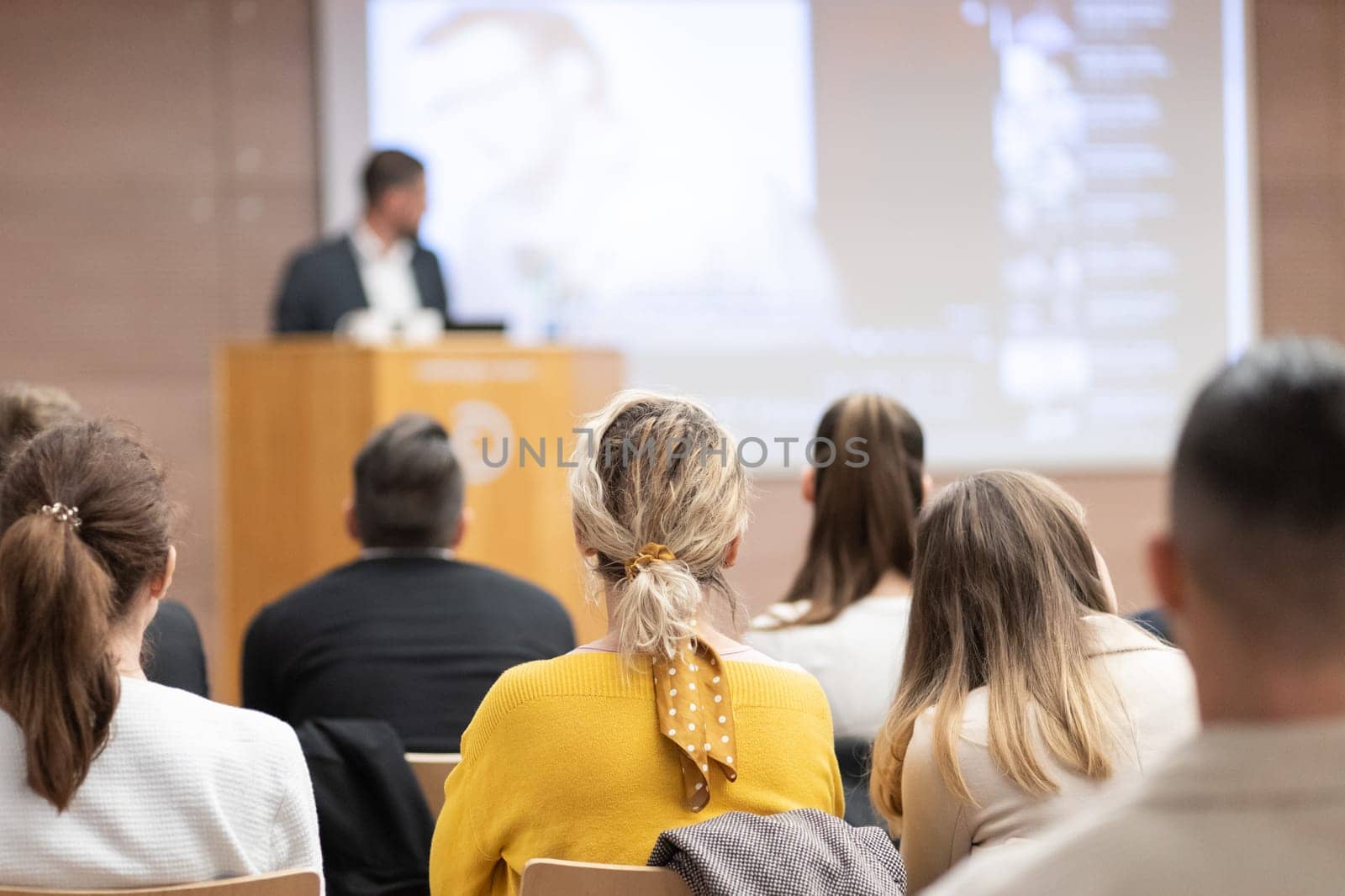 Speaker giving a talk in conference hall at business event. Rear view of unrecognizable people in audience at the conference hall. Business and entrepreneurship concept