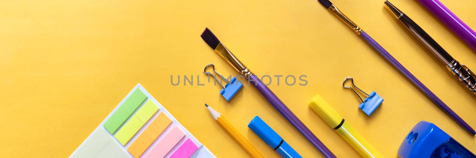 Frame from school and office supplies Paper clips, scissors, pens, felt-tip pens, sharpener, isolated on yellow background. Flat lay.Back to school, education concept.Teacher's Day. by YuliaYaspe1979