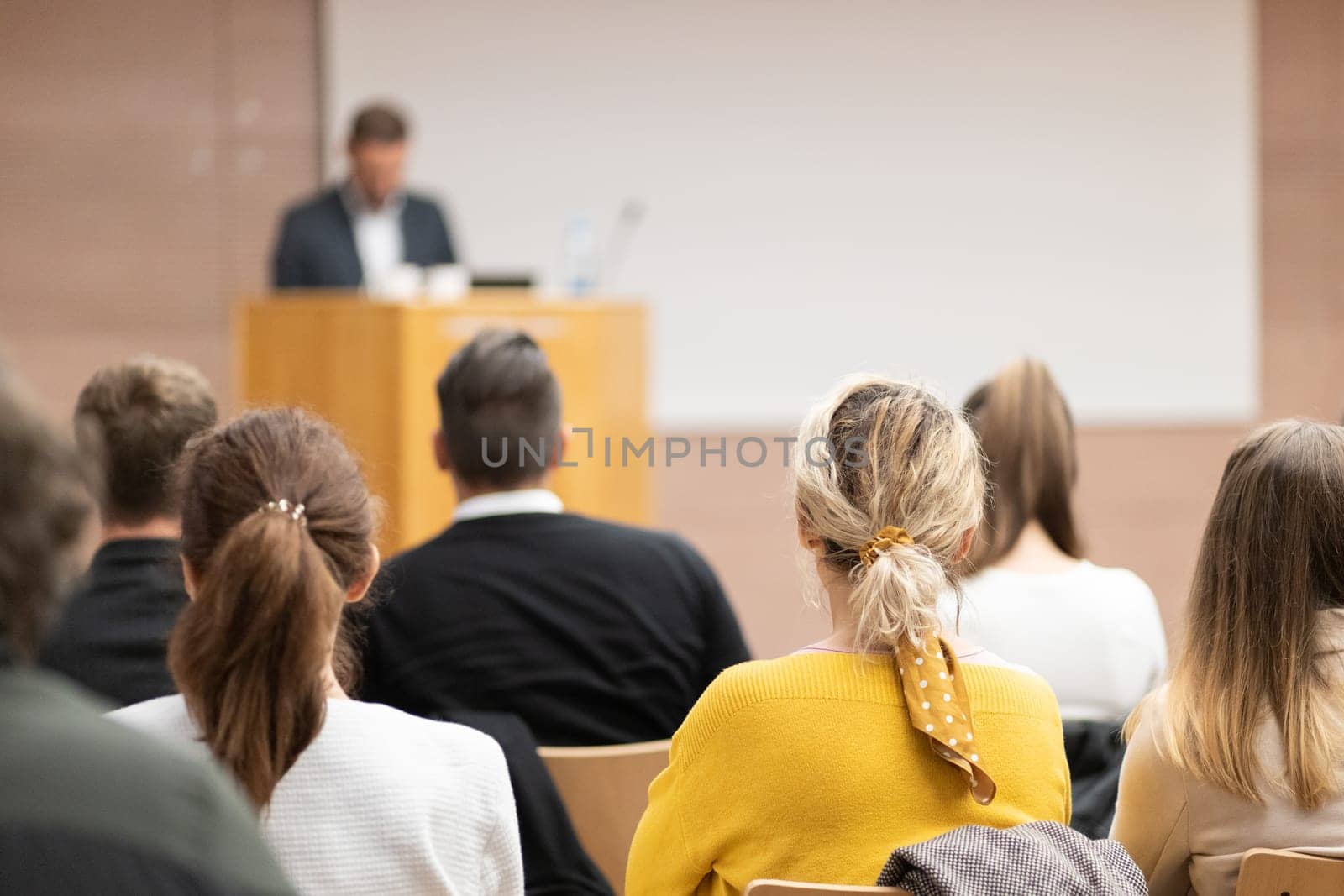 Speaker giving a talk in conference hall at business event. Rear view of unrecognizable people in audience at the conference hall. Business and entrepreneurship concept