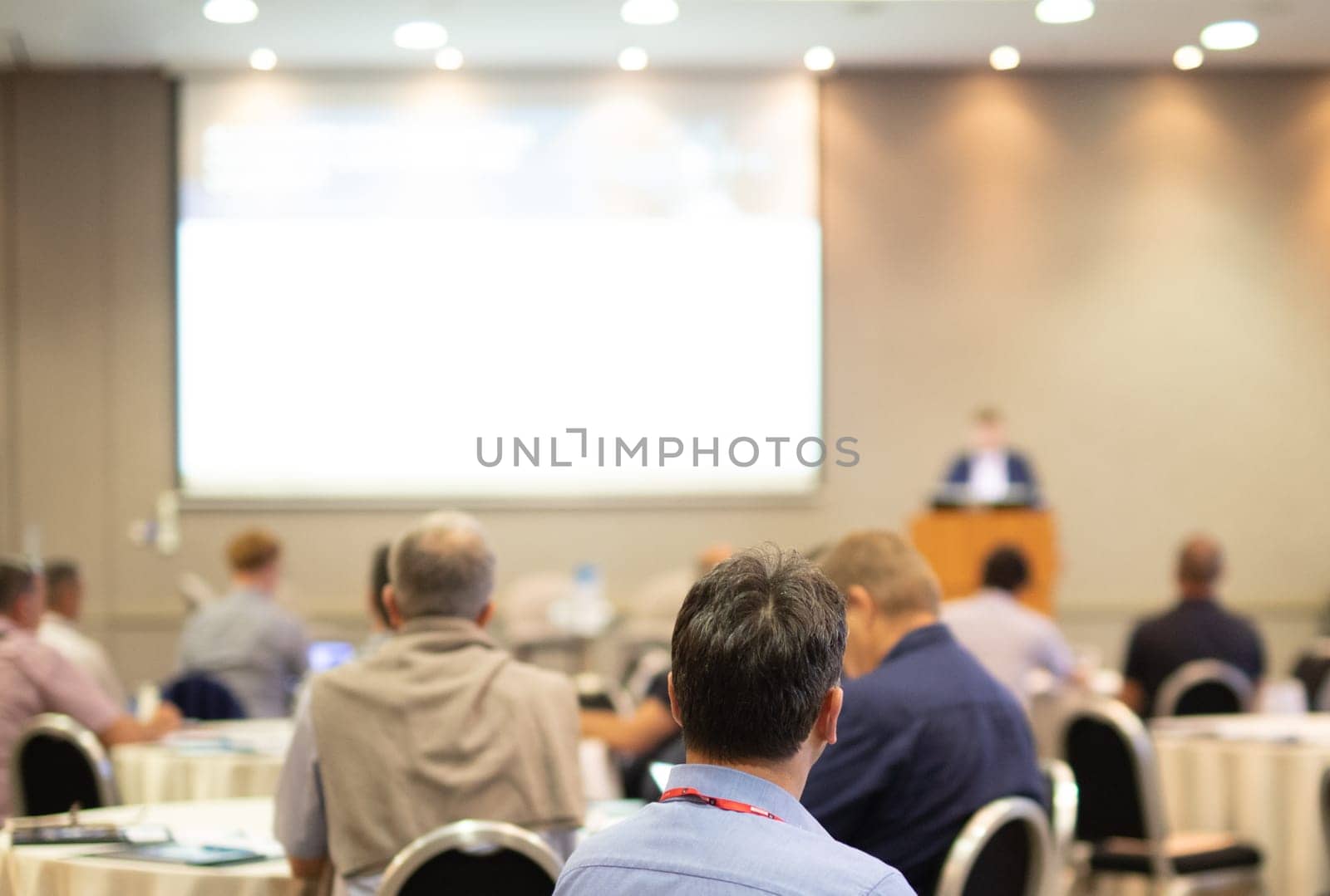 Speaker giving a talk in conference hall at business event. Rear view of unrecognizable people in audience at the conference hall. Business and entrepreneurship concept