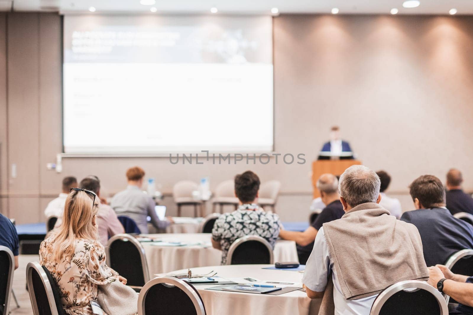 Speaker giving a talk in conference hall at business event. Rear view of unrecognizable people in audience at the conference hall. Business and entrepreneurship concept. by kasto