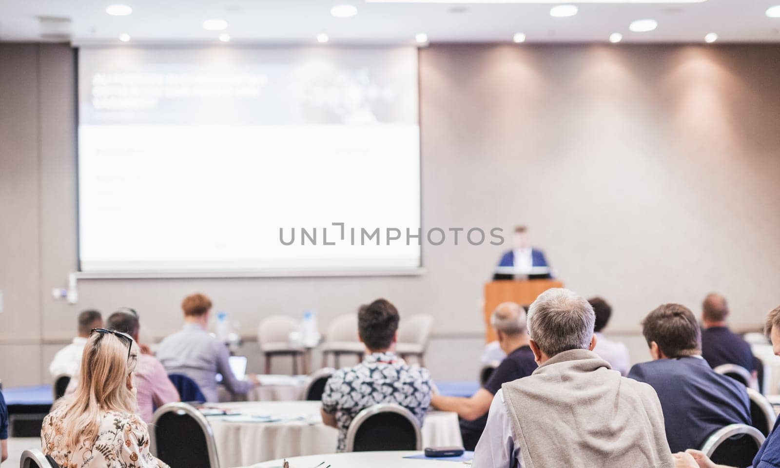 Speaker giving a talk in conference hall at business event. Rear view of unrecognizable people in audience at the conference hall. Business and entrepreneurship concept