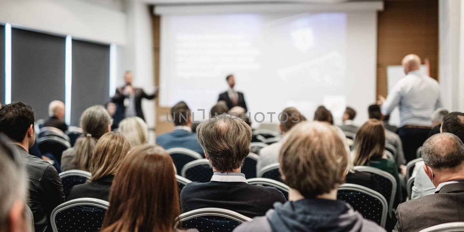 I have a question. Group of business people sitting at the chairs in conference hall. Businessman standing up asking a question. Conference and Presentation. Business and Entrepreneurship.