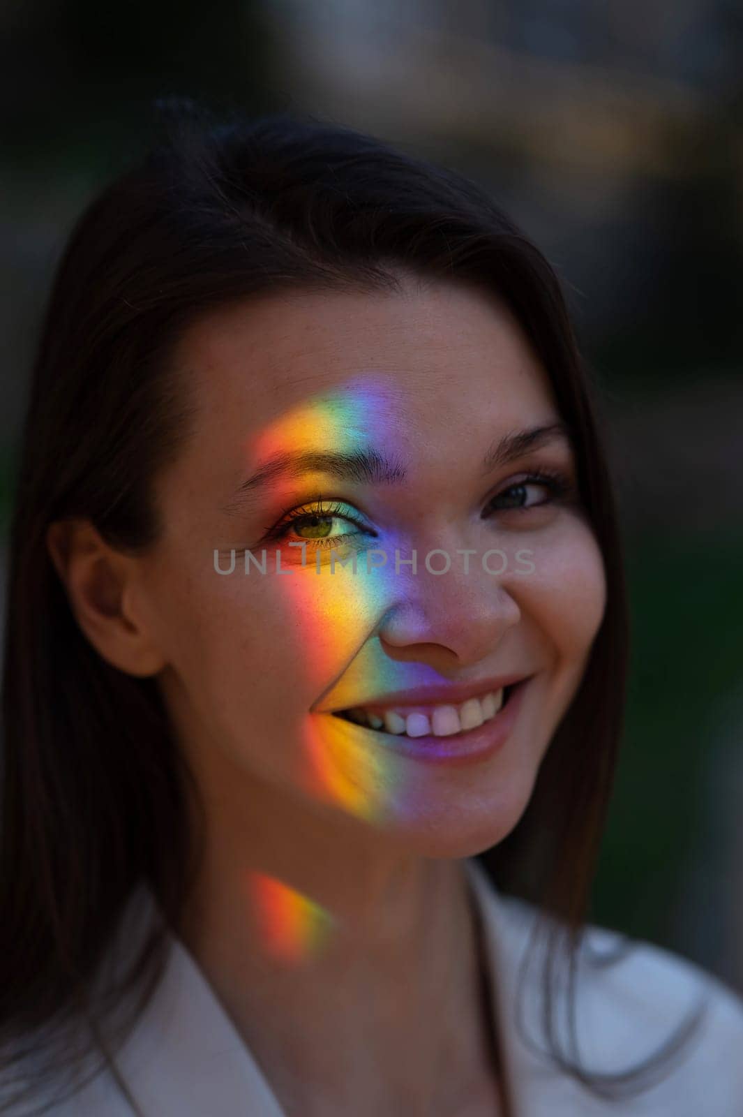 Portrait of caucasian woman with rainbow beam on her face outdoors. by mrwed54