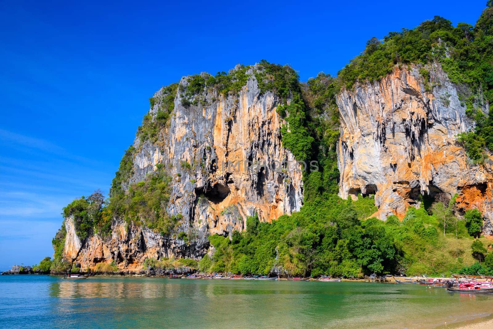 Long tail boats along cliff rocks near the beach, Tonsai Bay, Railay Beach, Ao Nang, Krabi, Thailand.