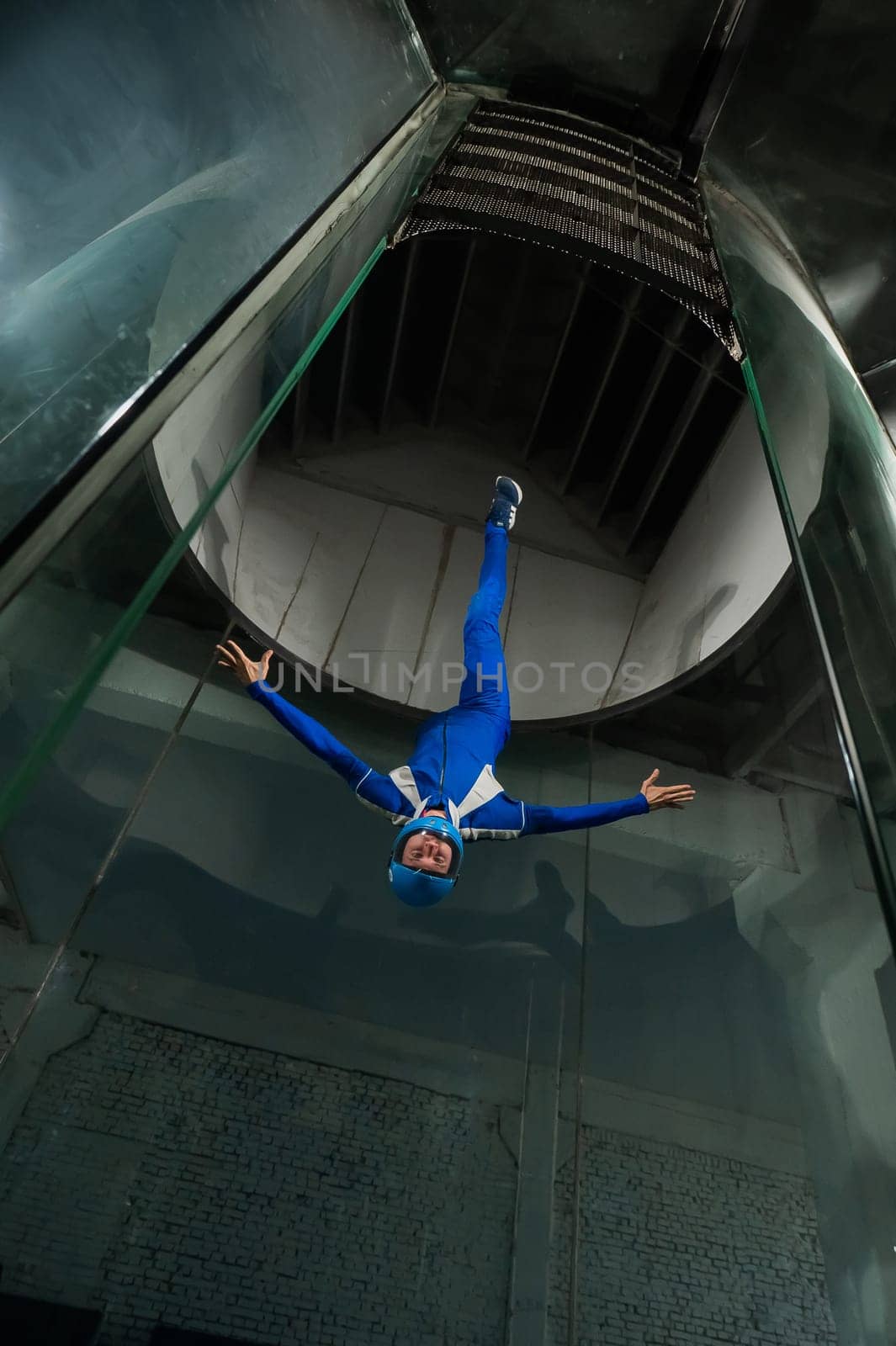 A man in overalls and a protective helmet enjoys flying in a wind tunnel. Free fall simulator.