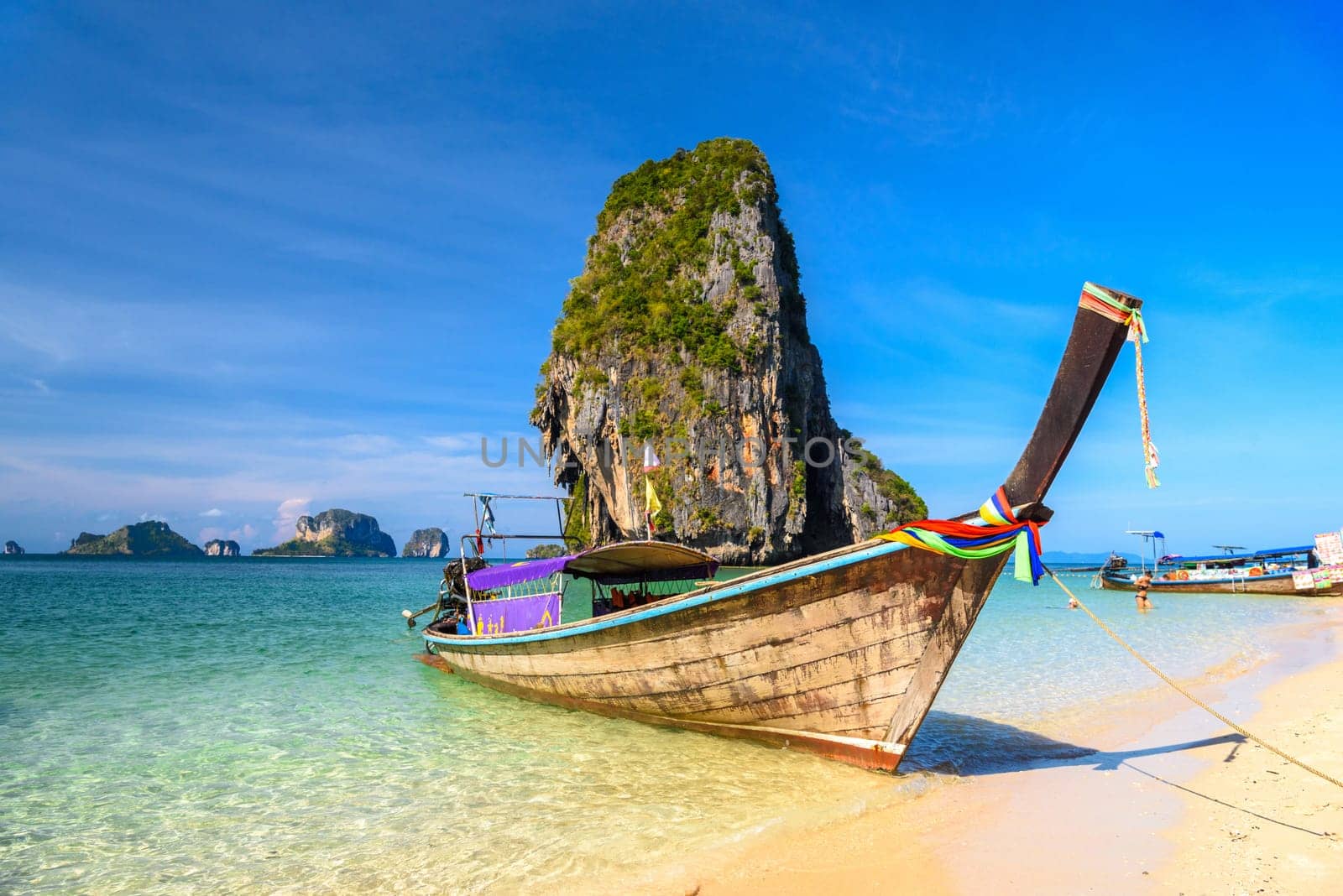 Long tail boats and cliff rock in azure water, Ko Rang Nok, Ao Phra Nang Beach, Ao Nang, Krabi, Thailand.