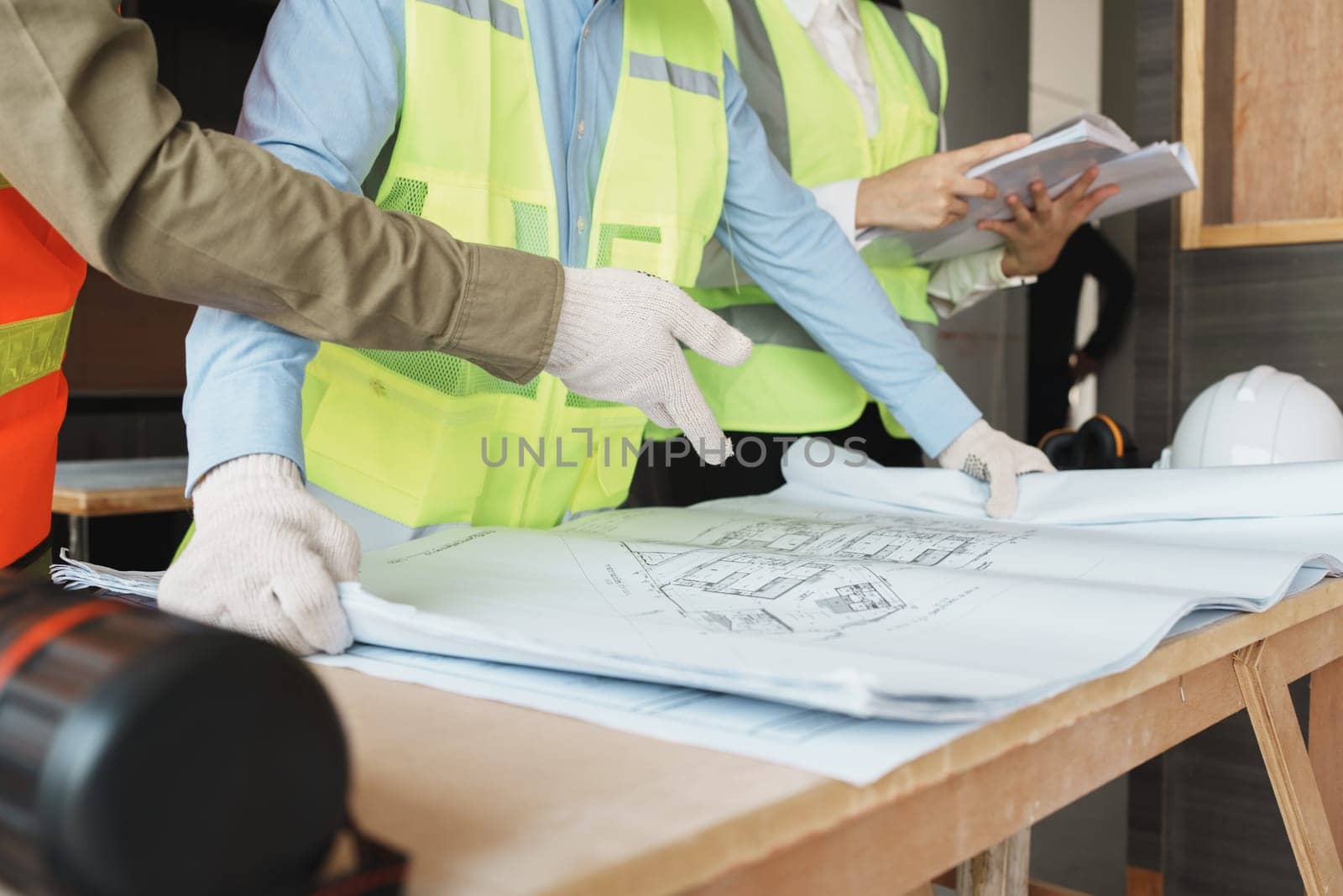 multi ethnic engineer brainstorming and measuring for cost estimating on blueprint and floor plan drawings about design architectural and engineering for houses and buildings.