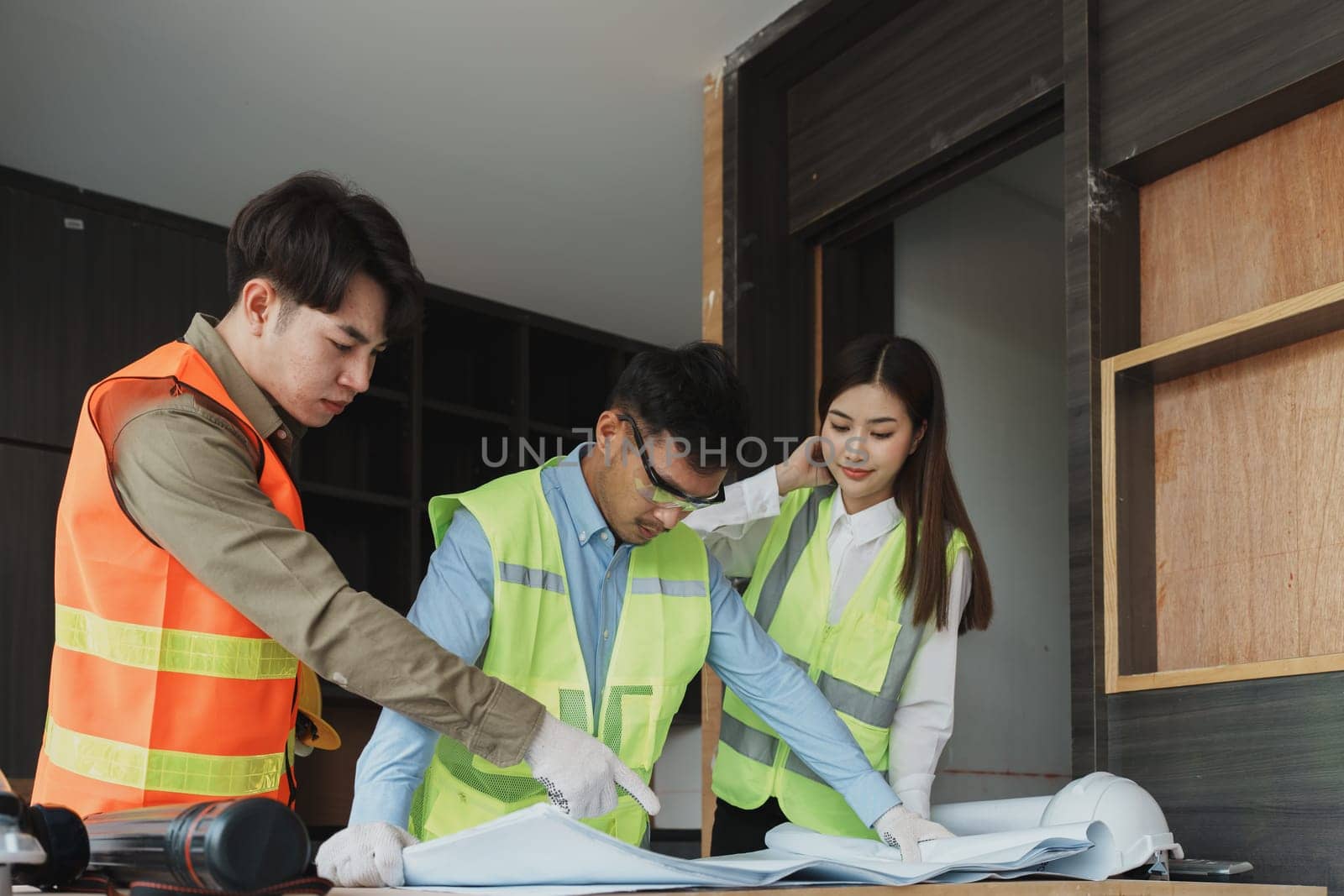 multi ethnic engineer brainstorming and measuring for cost estimating on blueprint and floor plan drawings about design architectural and engineering for houses and buildings.