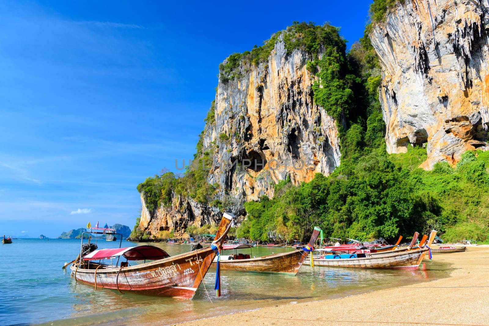 KRABI, THAILAND- MARCH 2018: Long tail boat on tropical beach with palms, Tonsai Bay, Railay Beach, Ao Nang, Krabi, Thailand.