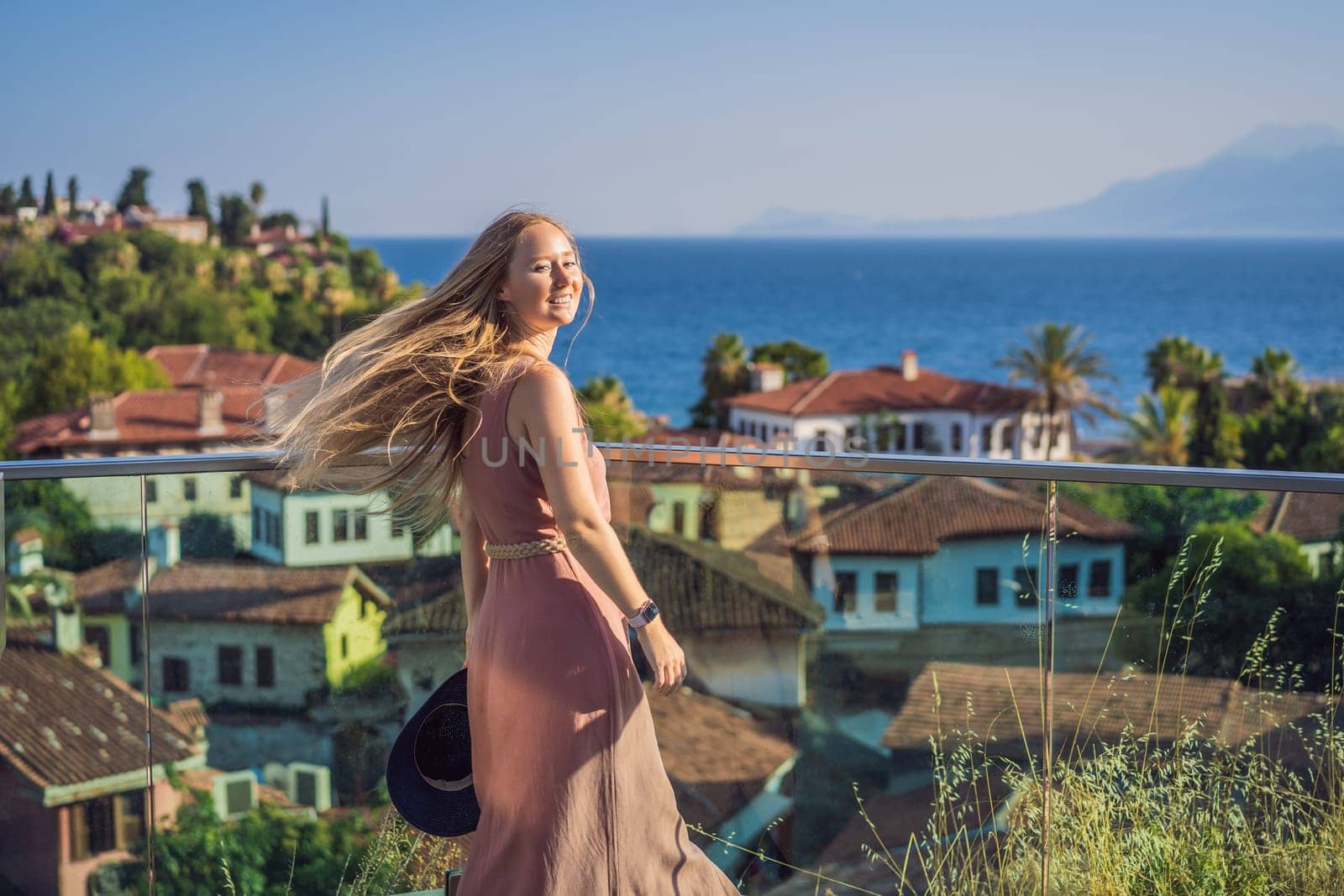 Woman tourist in Old town Kaleici in Antalya. Turkiye. Panoramic view of Antalya Old Town port, Taurus mountains and Mediterrranean Sea, Turkey.