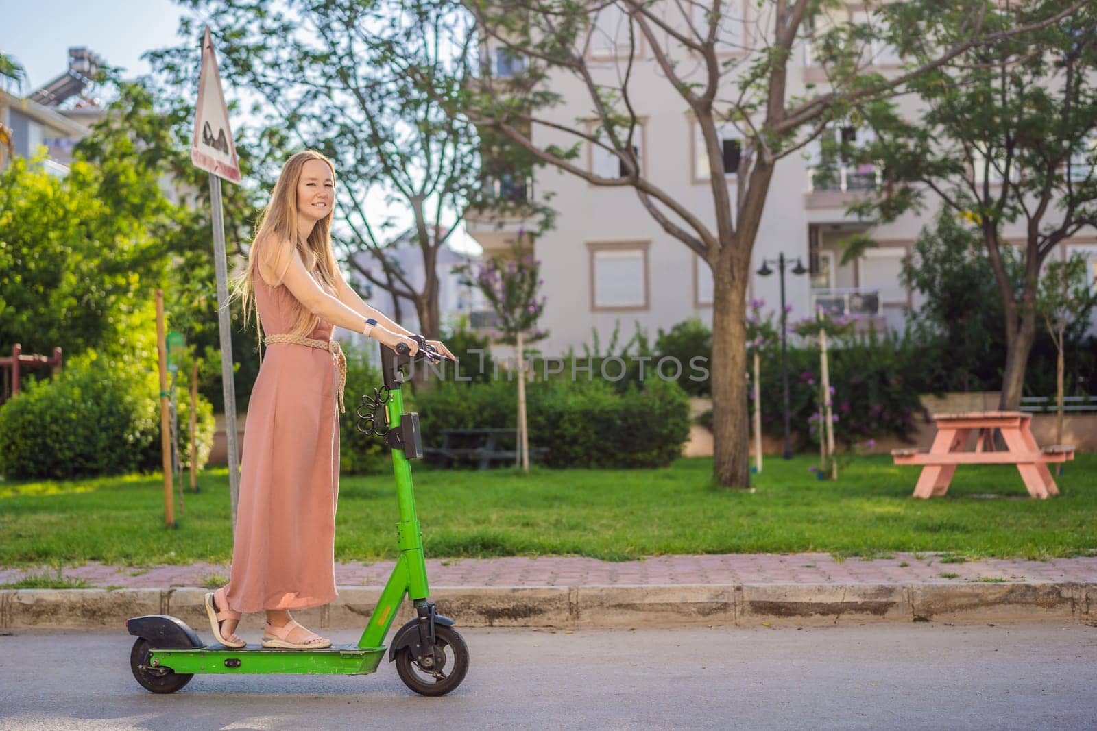 Young beautiful woman riding an electric scooter to work, modern girl, new generation, electric transport, ecology, ecological transport, sunset, electric skateboard.