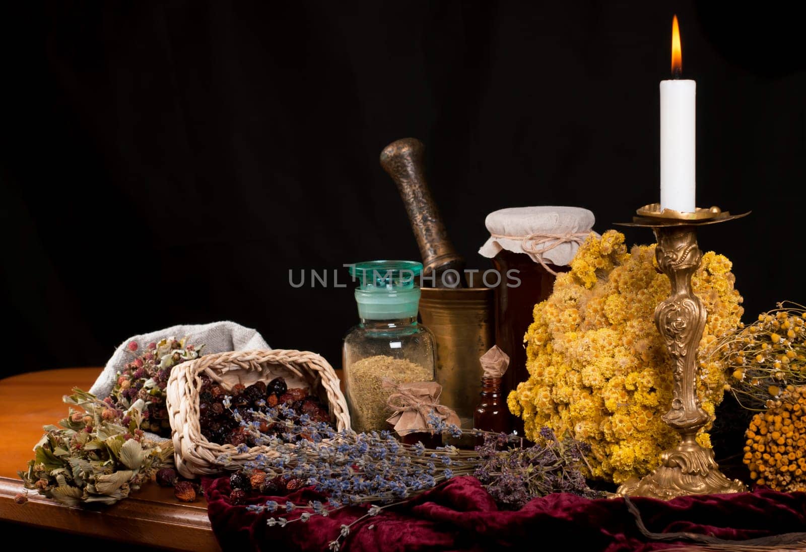 Dried healing herbs, flowers and candles, ritual purification , copyspace Close up of healing herbs alchemist stuff. Old pharmacy, alternative medicine concept. mortar and pestle. on a black background. wooden table. Front view. by aprilphoto