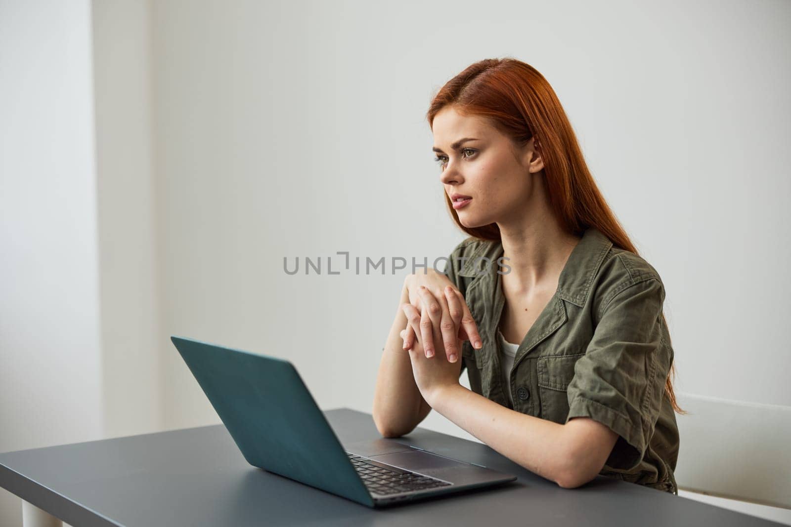 a woman sits at work at the table and looks thoughtfully, solving work issues in the office by Vichizh