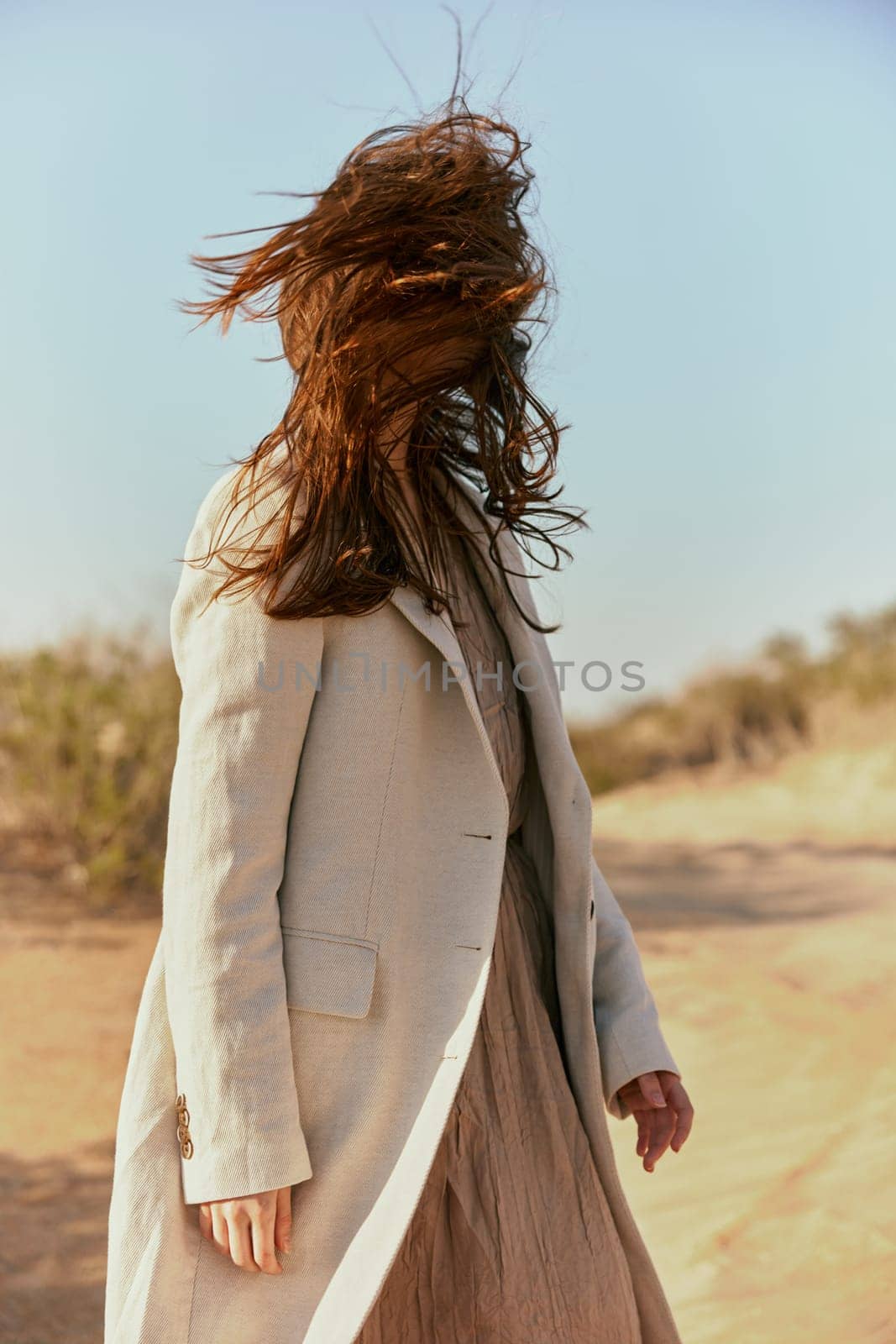 portrait of a woman in a light jacket with hair covering her face from the wind. High quality photo