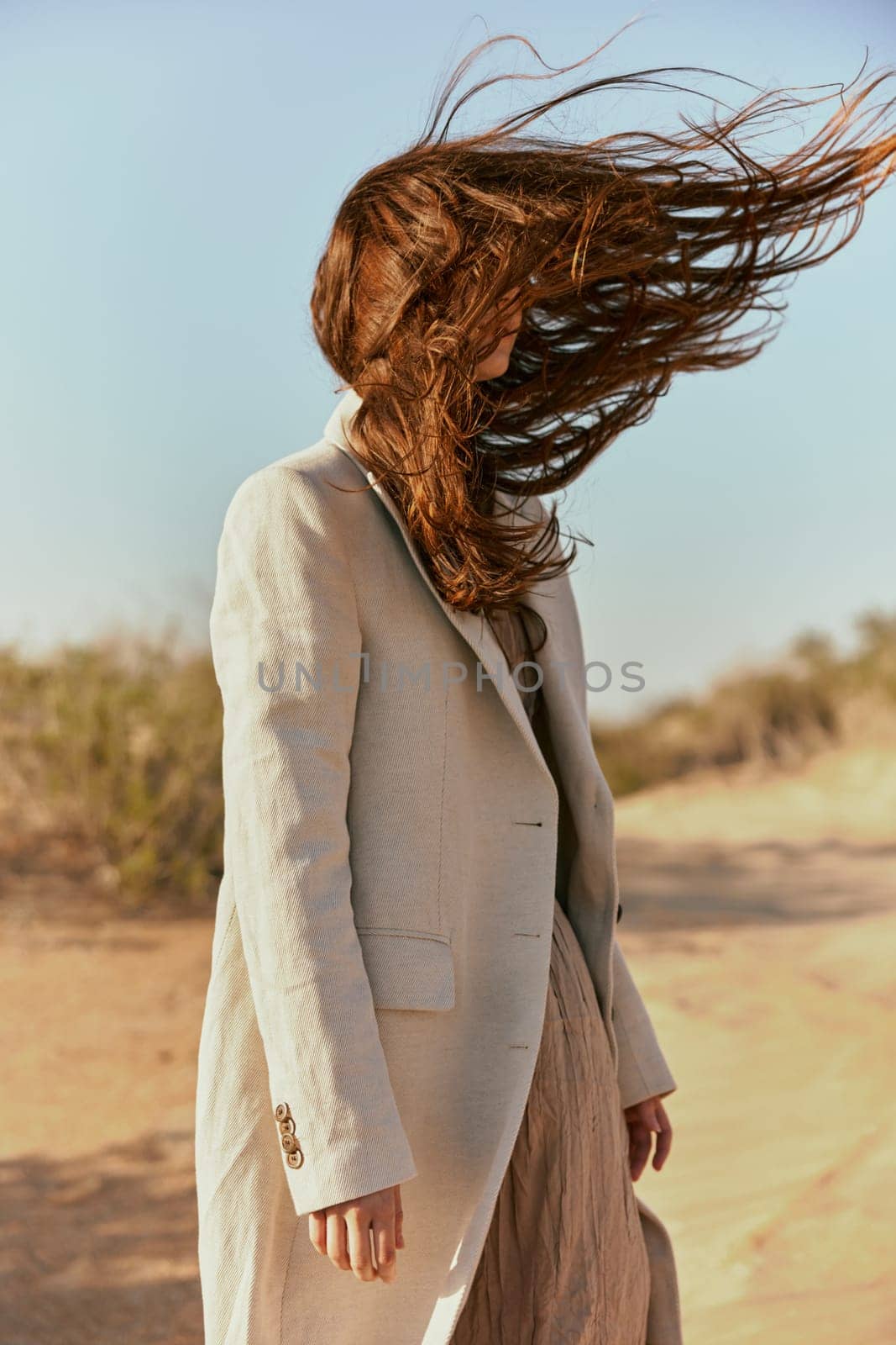 portrait of a woman in a light jacket with hair covering her face from the wind by Vichizh