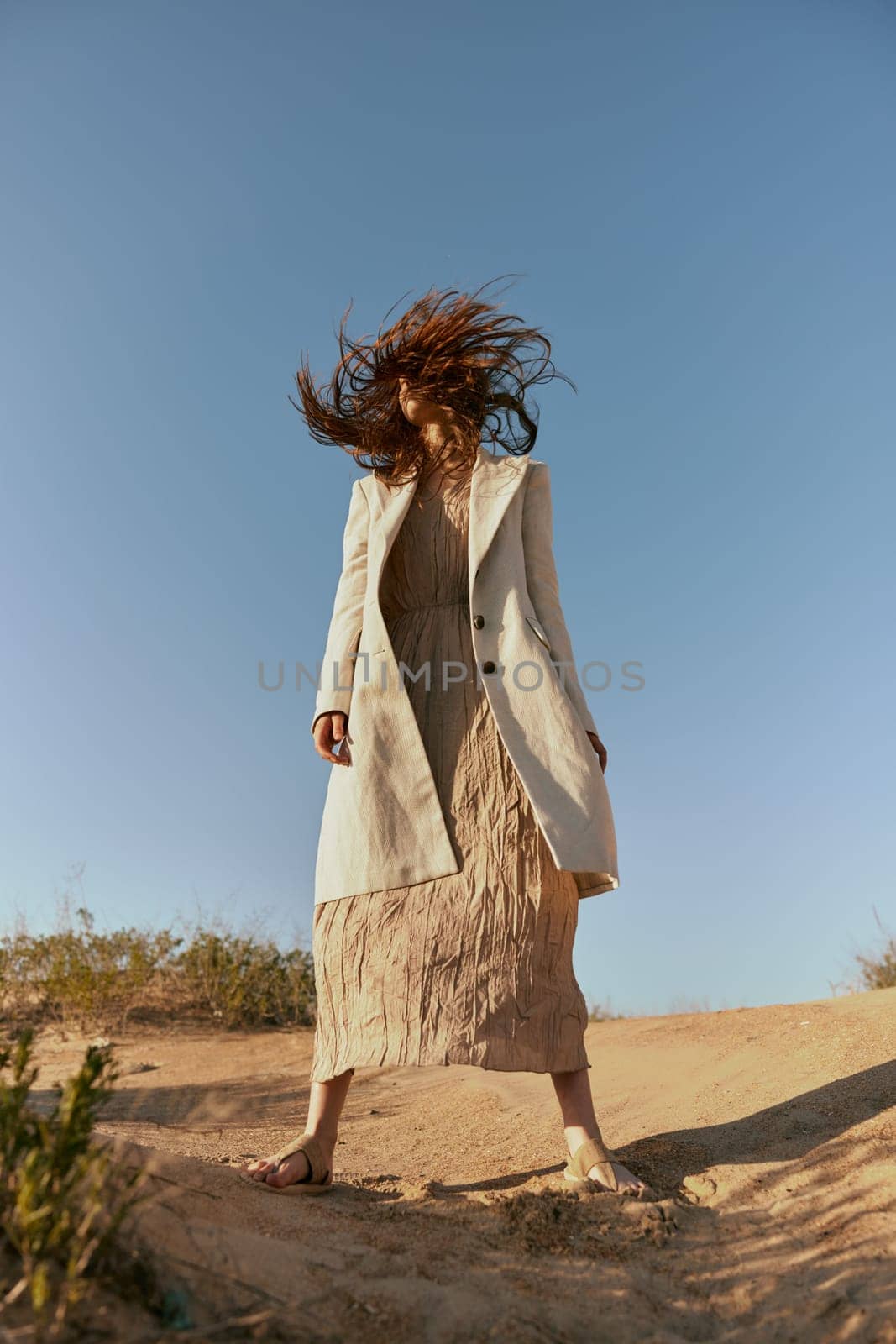 stylish woman in a light jacket posing in nature covering her face with hair. High quality photo