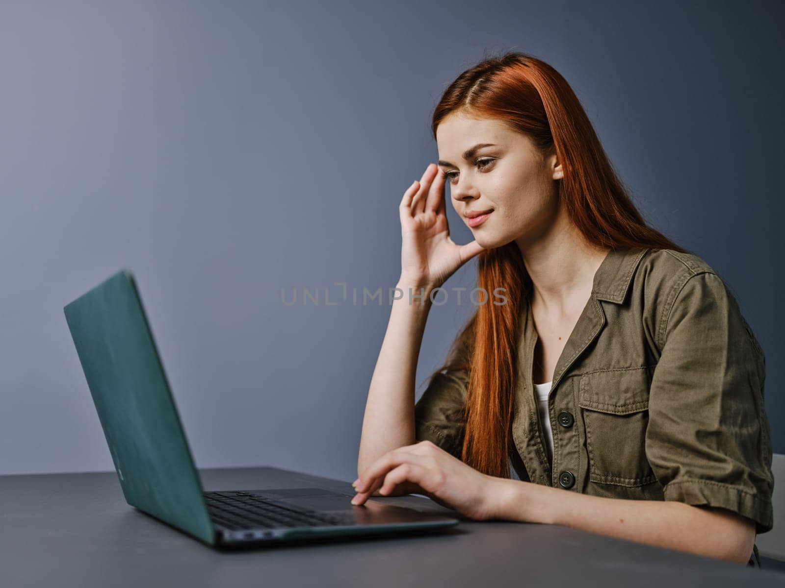 portrait of a happy redhead woman working on a laptop in the office. High quality photo