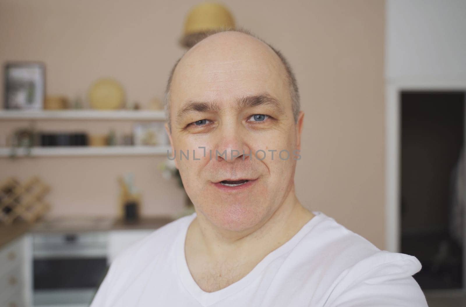 Smiling male blogger taking a selfie or video call from his apartment.