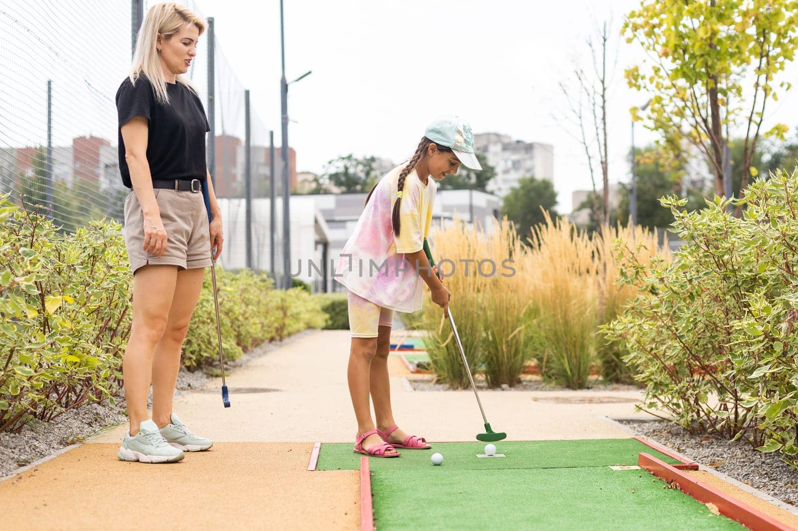 mother and daughter playing mini golf, children enjoying summer vacation by Andelov13